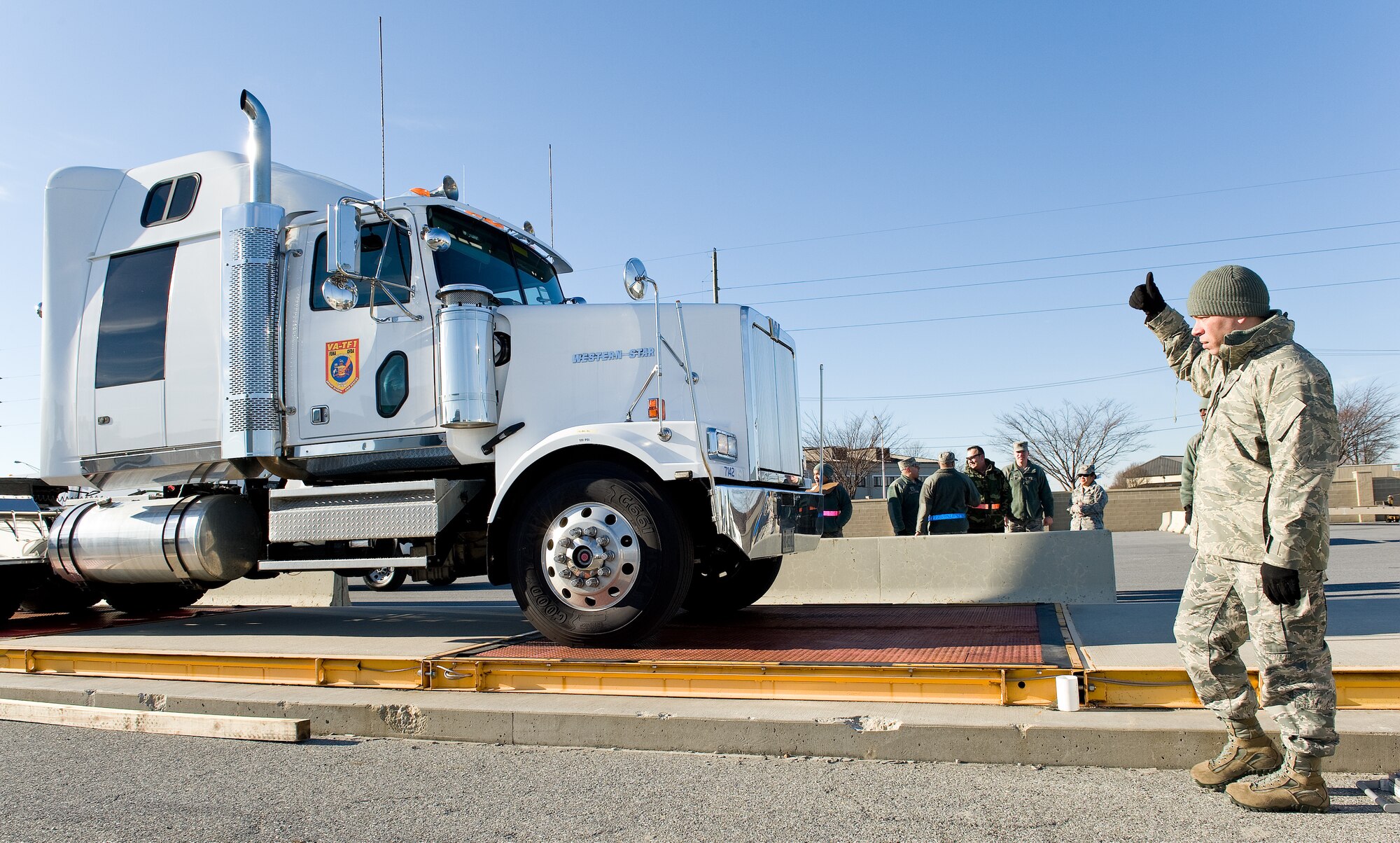 Tech. Sgt. Aaron Adcock, 74th Aerial Port Squadron special handling specialist, Joint Base San Antonio-Lackland, Texas, signals driver Archie Fellows, Fairfax County Fire and Rescue Department, Va.: Virginia Task Force 1 driver/mechanic, to proceed onto the scales March 3, 2016, at the 436th APS marshalling yard on Dover Air Force Base, Del. Fellows drove the truck and 48-foot trailer onto the scales to be weighed individually that netted a combined total weight of 56,000 pounds. (U.S. Air Force photo/Roland Balik