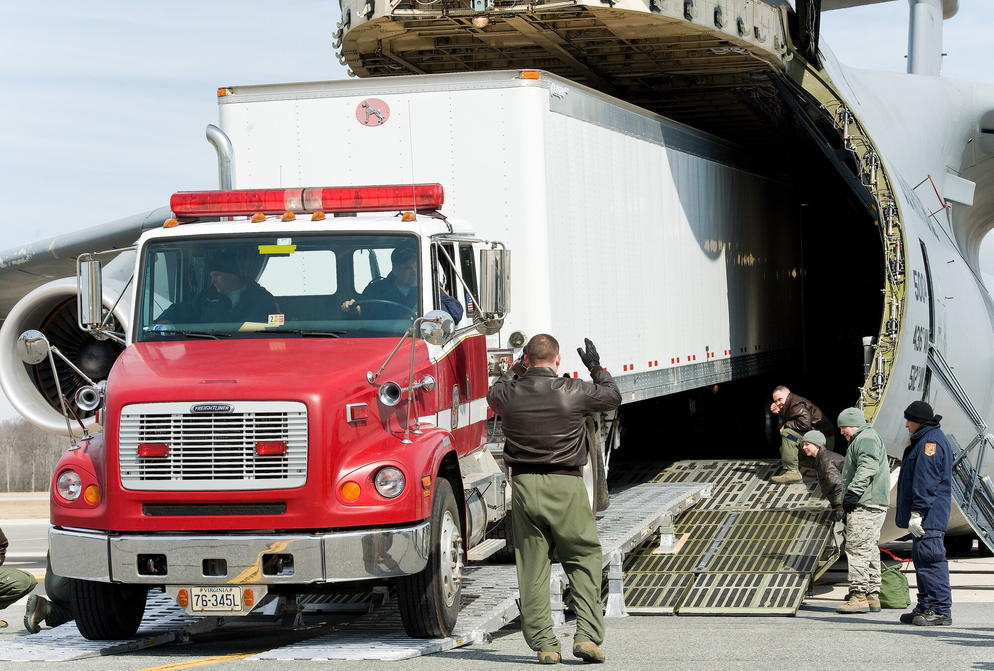 Tech. Sgt. Frederick Raffaelli, 9th Airlift Squadron loadmaster, marshals Jimmie Richards, Fairfax County Fire and Rescue Department, Va.: Virginia Task Force 1 driver/mechanic, as he drives a Western Star Constellation truck attached to a 54-foot Great Dane trailer backwards into the cargo compartment of a C-5M Super Galaxy March 3, 2016, on Dover Air Force Base, Del. Richards backed the 92,000-pound truck and trailer into the cargo compartment using a new loading ramp system known as DAMAS 26K which stands for DOMOPS Airlift Modular Approach Shoring. The 900-pound DAMAS 26K can be set up by two or three individuals in 14 minutes, replacing an antiquated 6,000 pound wood shoring kit that required a team of personnel and a forklift to set up. (U.S. Air Force photo/Roland Balik)
