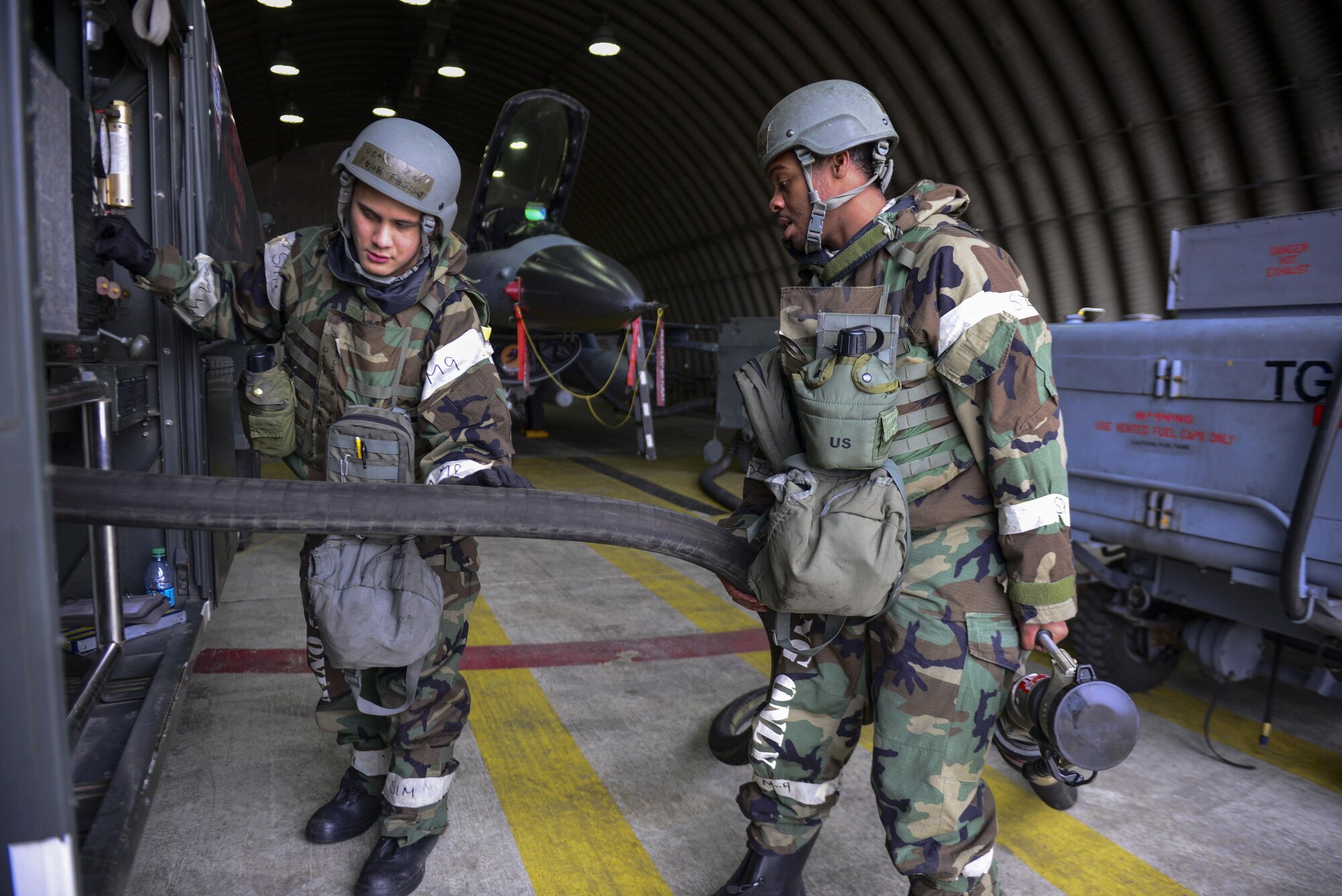 Senior Airman Elijah Padilla and Airman 1st Class Everald Marsh, 51st Logistics Readiness Squadron, rewind a fuel hose after refueling an F-16 Fighting Falcon during readiness exercise Beverly Midnight 16-01, March 8, 2016, at Osan Air Base, Republic of Korea. Across the base, LRS Airmen are working day and night providing fuels support for the constant aircraft generations. (U.S. Air Force photo by Staff Sgt. Jonathan Steffen/Released)