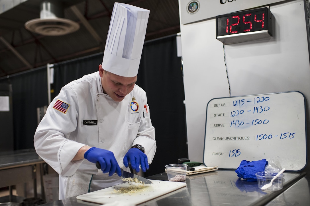 U.S. Army Reserve Culinary Arts Team member Sgt. Joshua Barnhill, with the 377th Theater Sustainment Command, chops ingredients during the Nutritional Hot Food Challenge category at the 41st Annual Military Culinary Arts Competitive Training Event, March 8, 2016, at Fort Lee, Va. Parker and Barnhill earned a silver in the category with their roasted beet salad, pan-seared trout, and eggless, milkless spice cake, all coming in at under 850 calories. (U.S. Army photo by Timothy L. Hale) (Released)