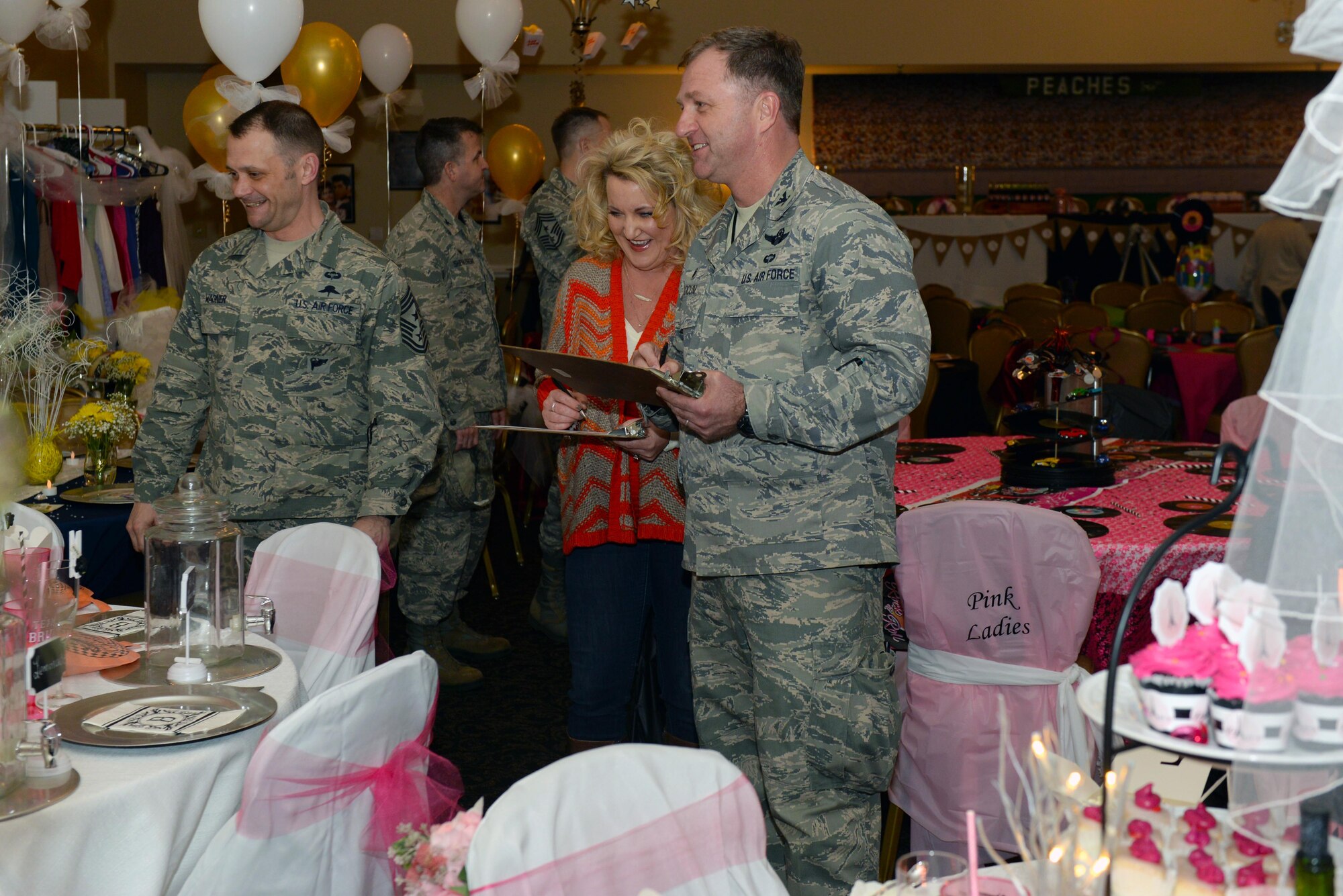 Chief MSgt. Shane Wagner (left), 4th Fighter Wing command chief, Sarah Merritt (center), the Arts Council of Wayne County executive director, and Col. Mark Slocum (right), 4th Fighter Wing commander, judge tables for the inaugural Spouses Dining-in, March 5, 2016, at Seymour Johnson Air Force Base, North Carolina. The tables were judged on elements such as creativity, hand-made items and originality. (U.S. photo/Airman 1st Class Ashley Williamson)