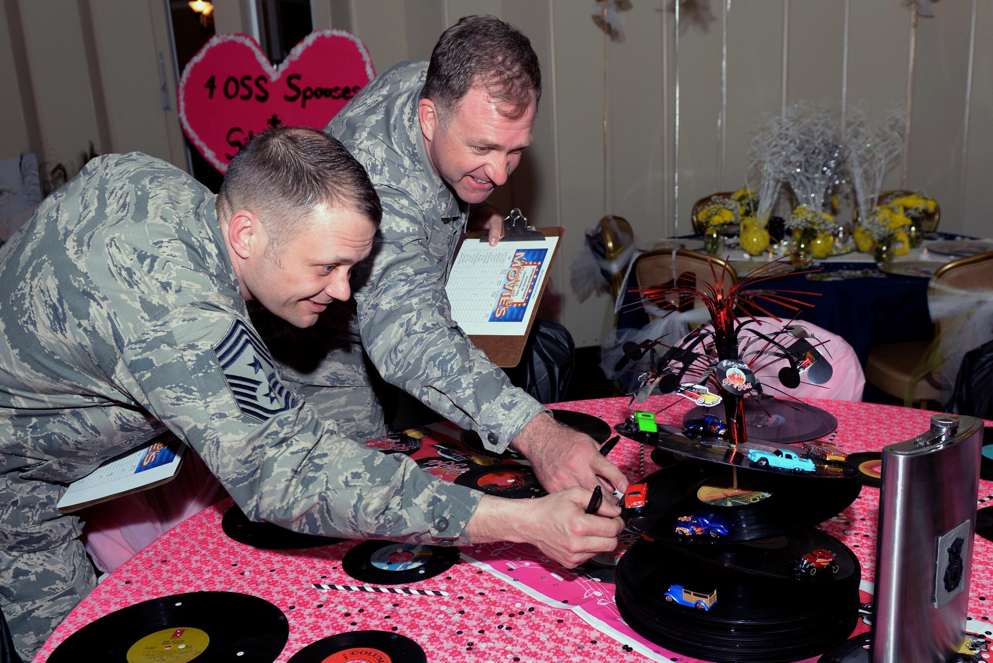 Chief MSgt. Shane Wagner (left), 4th Fighter Wing command chief, and Col. Mark Slocum (right), 4th Fighter Wing commander, inspect a table for the first-ever Spouses Dining-in, March 5, 2016, at Seymour Johnson Air Force Base, North Carolina. Approximately 100 people attended the dining-in dressed as characters from the movie theme of their squadron’s table. (U.S. photo/Airman 1st Class Ashley Williamson)