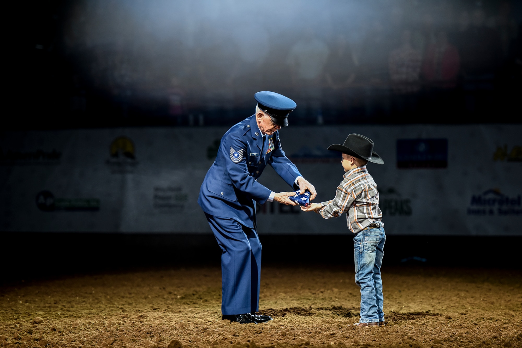 U.S. Army and Air Force veteran Master Sgt. Tom Davis receives a folded American flag from a young local resident during the opening ceremony for Military Appreciation Night as part of the 84th annual San Angelo Stock Show and Rodeo at Foster Communications Coliseum in San Angelo, Texas, Feb. 17, 2016. The rodeo honored military members from all generations. (U.S. Air Force photo by Senior Airman Devin Boyer/Released)