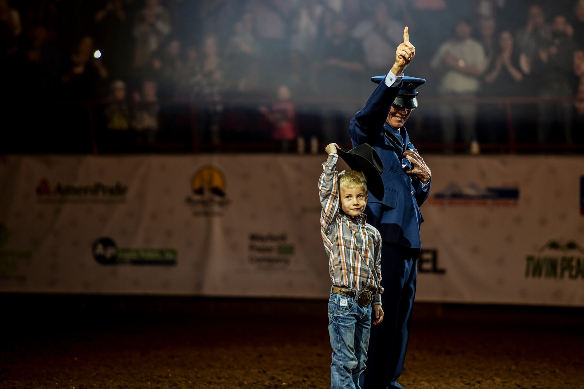 U.S. Army and Air Force veteran Master Sgt. Tom Davis, right, and a young local resident wave to the audience during the opening ceremony for Military Appreciation Night as part of the 84th annual San Angelo Stock Show and Rodeo at Foster Communications Coliseum in San Angelo, Texas, Feb. 17, 2016. The rodeo honored military members from all generations. (U.S. Air Force photo by Senior Airman Devin Boyer/Released)