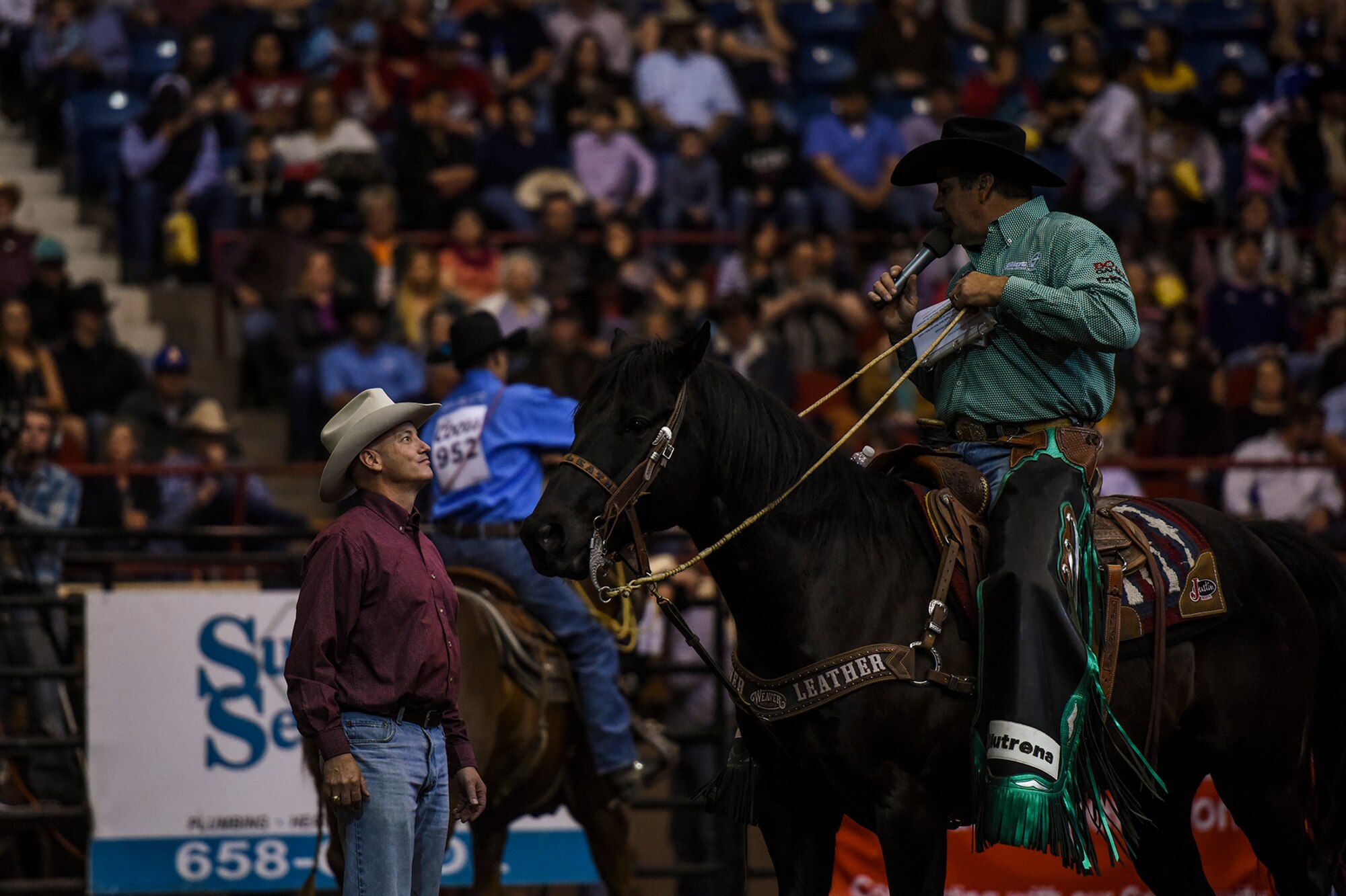 Boyd Polhamus, San Angelo Stock Show and Rodeo announcer, recognizes U.S. Air Force Col. Michael L. Downs, 17th Training Wing Commander, during Military Appreciation Night at Foster Communications Coliseum in San Angelo, Texas, Feb. 17, 2016. Downs participated in the rodeo during the tie-down roping as per tradition. After officials released the calf, he returned the rope to the cowboy. (U.S. Air Force photo by Senior Airman Devin Boyer/Released)