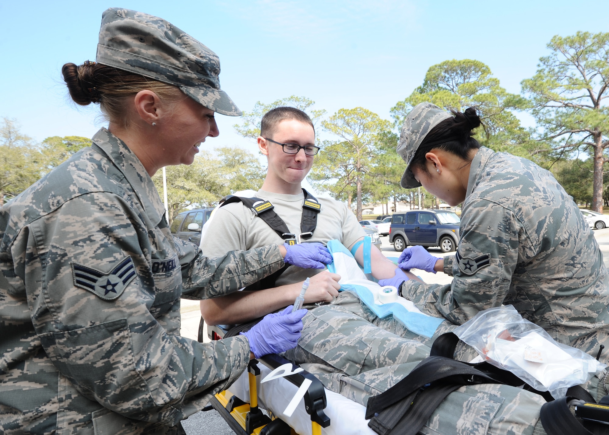 Senior Airman Casey O’Neill and Airman 1st Class Emily Stickney, 325th Medical Operations Squadron ambulance services technicians, perform an emergency intravenous access demonstration on Senior Airman Benjamin Friedrichsen, 325th MDOS ambulance services technician, March 3 at the 325th Medical Group. The Ambulance Service Department partners with the 325th Civil Engineer Squadron Fire Department and the 325th Security Forces Squadron to provide 24/7 emergency medical response and support for everyone on Tyndall AFB and provides first-responder support from the DuPont Bridge to Mexico Beach. (U.S. Air Force photo by Senior Airman Ty-Rico Lea)