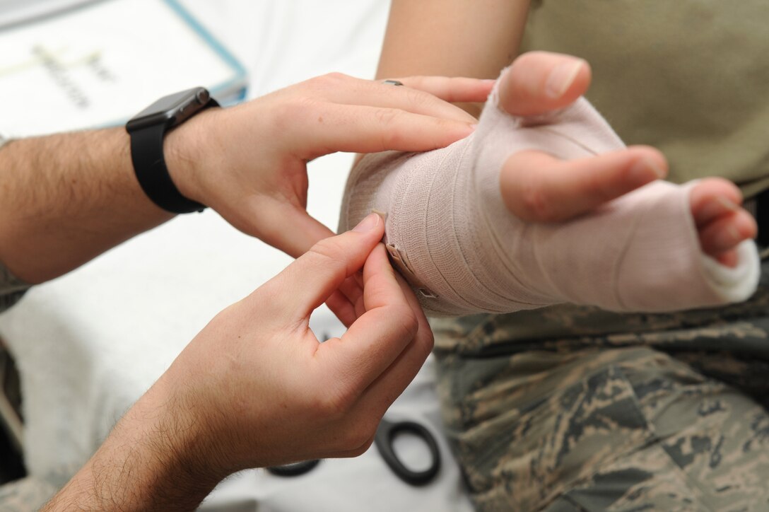 U.S. Air Force Staff Sgt. Christopher Leonard, a paramedic assigned to the 633rd Medical Operations Squadron, wraps the arm of Airman 1st Class Lindsey Schmalfeldt, an aerospace medical technician assigned to the 633rd MDOS, during on-the-job training at Langley Air Force Base, Va., March 7, 2016. A wrap is applied after the splint to help hold it in place, properly immobilizing the potential fracture. (U.S. Air Force photo by Senior Airman Brittany E. N. Murphy)