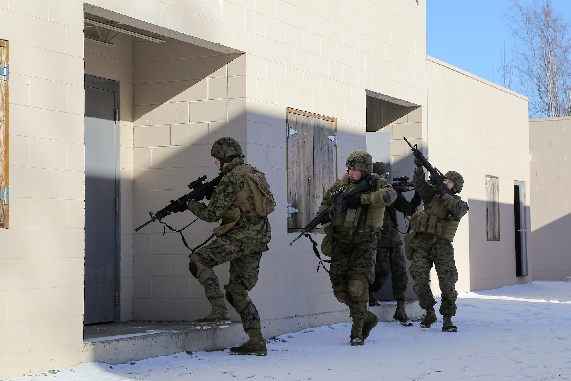 U.S. Marines assigned to Detachment Military Police Company D, 4th Law Enforcement Battalion, assault and clear a complex during military operations on urban terrain (MOUT) training at Joint Base Elmendorf-Richardson, Alaska, March 6, 2016. The MOUT training prepared the Marines for their upcoming deployment to Serbia where they will serve as military police advisors. (U.S. Air Force photo/Alejandro Pena)