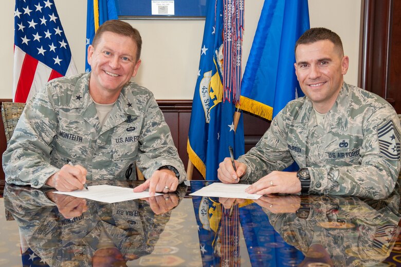 Brig. Gen. Wayne Monteith, 45th Space Wing commander, and Chief Master Sgt. Jason Lamoureux, 45th SW command chief, make their contribution to the Air Force Assistance Fund at Patrick Air Force Base, Fla., March 9, 2016. The campaign runs from March 23 to May 1, 2016, and benefits the Air Force Aid Society, Air Force Village, Air Force Enlisted Village and General and Mrs. Curtis LeMay Foundation. Members can contact their unit representative for more information. (U.S. Air Force photo by Benjamin Thacker) (Released)