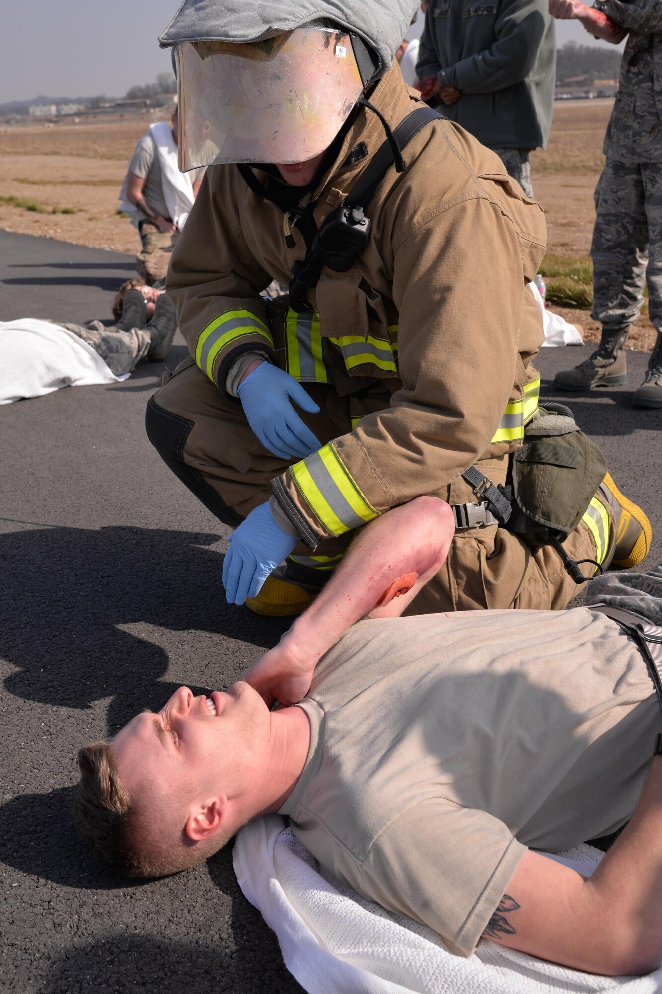 Airman 1st Class Joshua Scott, 51st Civil Engineer Squadron firefighter, examines a simulated injured victim during Exercise Beverly Midnight 16-01, March 9, 2016, at Osan Air Base, Republic of Korea. This scenario involved a C-130H Hercules cargo aircraft assigned to the 374th Airlift Wing from Yokota Air Base, Japan, which took simulated small-arms fire from opposing forces upon landing. Emergency responders from the fire department, security forces and medical group swarmed the scene to provide assistance to the simulated causalities. (U.S. Air Force photo by Staff Sgt. Benjamin Sutton/Released) 