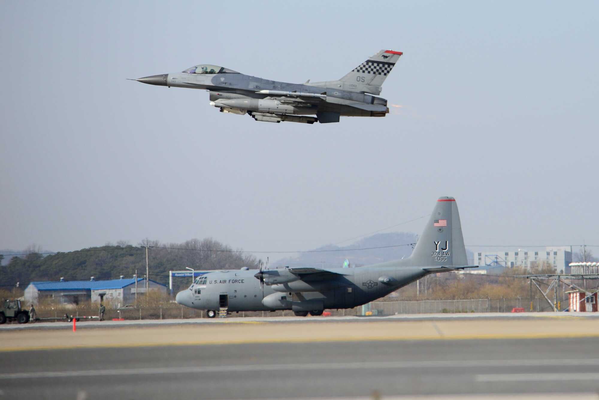 An F-16 Fighting Falcon from the 36th Fighter Squadron takes off while an a C-130H Hercules cargo aircraft assigned to the 374th Airlift Wing from Yokota Air Base, Japan, taxis during during Exercise Beverly Midnight 16-01, March 9, 2016, at Osan Air Base, Republic of Korea. Beverly Midnight is an exercise designed to evaluate the ability of personnel to survive and operate in simulated wartime conditions. (U.S. Air Force photo by Staff Sgt. Jonathan Steffen/Released) 