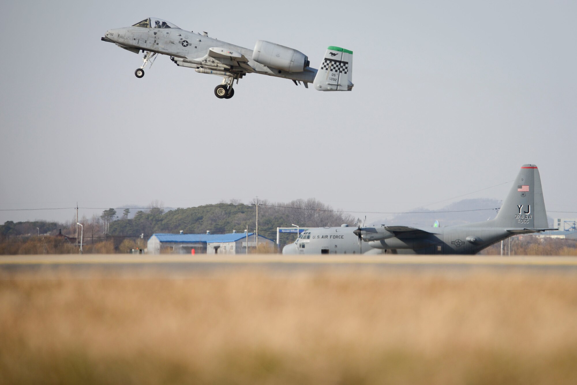 An A-10 Thunderbolt II from the 25th Fighter Squadron takes off while an a C-130H Hercules cargo aircraft assigned to the 374th Airlift Wing from Yokota Air Base, Japan, taxis during Exercise Beverly Midnight 16-01, March 9, 2016, at Osan Air Base, Republic of Korea. Beverly Midnight is a readiness exercise designed to evaluate the ability of personnel to survive and operate in simulated wartime conditions. (U.S. Air Force photo by Staff Sgt. Jonathan Steffen/ Released)