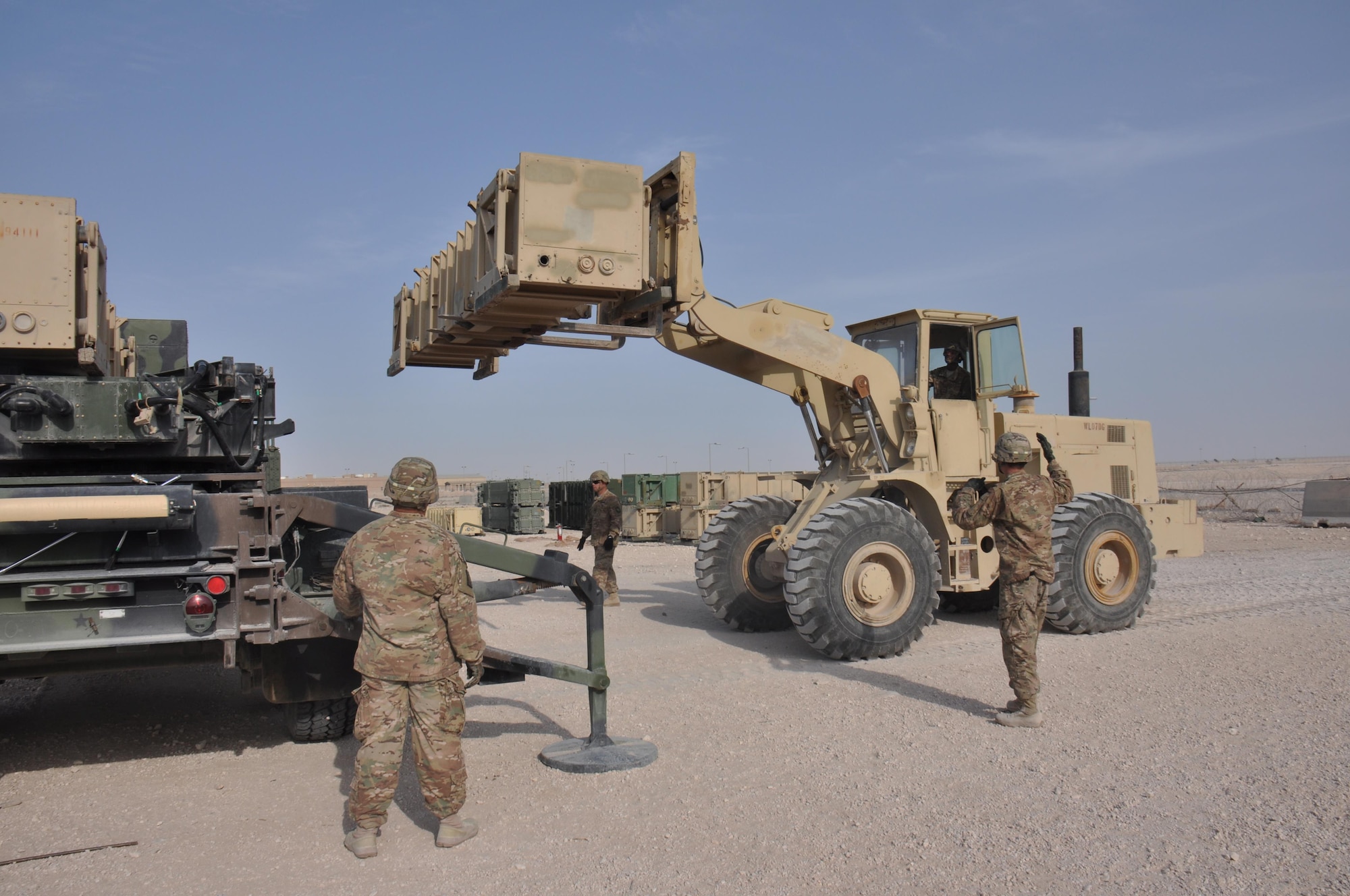 1-62 Delta Battery Air Defense Artillery Regiment Soldiers direct a forklift into position during a missile reloading training exercise at Al Udeid Air Base, Qatar Mar. 4. The Patriot missiles at AUAB protect the base from a variety of airborne threats including tactical ballistic missiles and drones.  (U.S. Air Force photo by Tech. Sgt. James Hodgman/Released)