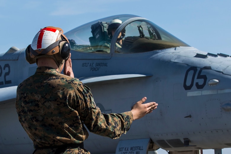 A Marine guides an F/A-18C Hornet aboard Marine Corps Air Station Beaufort March 7. Marine Fighter Attack Squadron 122 departed for the Western Pa¬cific March 7 as part of the Unit Deployment Program. More than 150 pilots and maintainers are participating in the deployment. The Marine is with with VMFA-122.