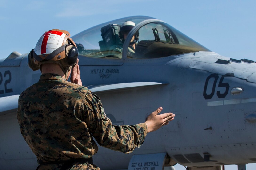 A Marine guides an F/A-18C Hornet at Marine Corps Air Station Beaufort, South Carolina March 7, 2016. Marine Fighter Attack Squadron 122 departed for the Western Pacific March 7 as part of the Unit Deployment Program. More than 150 pilots and maintainers are participating in the deployment. 