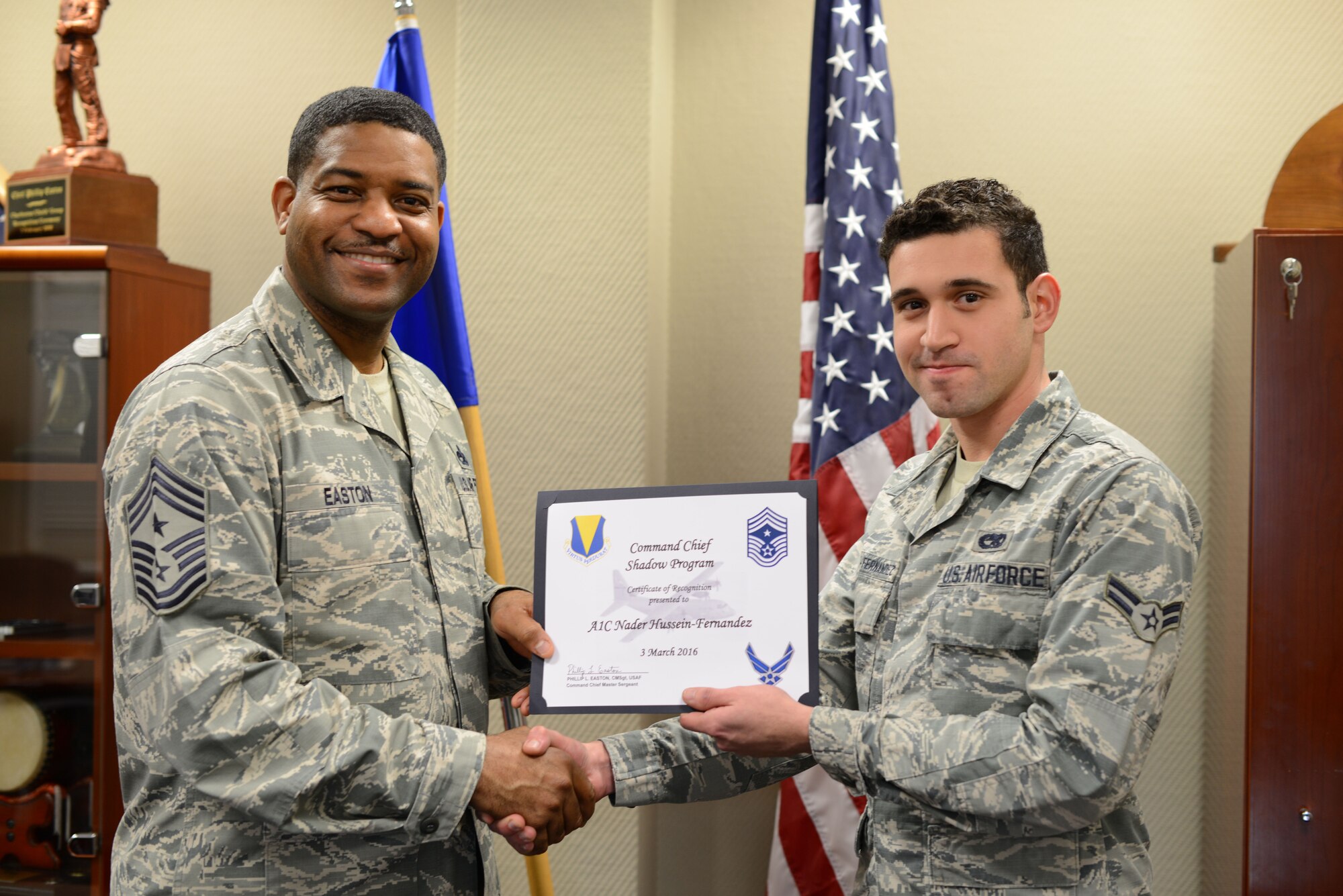 Airman First Class Nader Hussein-Fernandez, an aerospace ground equipment technician with the 86th Maintenance Squadron, receives a certificate of recognition from 86th Airlift Wing Command Chief Philip L. Easton, March 3, at Ramstein Air Base, Germany. Hussein-Fernandez was the first to participate in Easton’s shadow program at Ramstein, allowing him the opportunity to witness life as a wing command chief for a duty day. (U.S. Air Force photo/Tech. Sgt. Micky M. Pena)