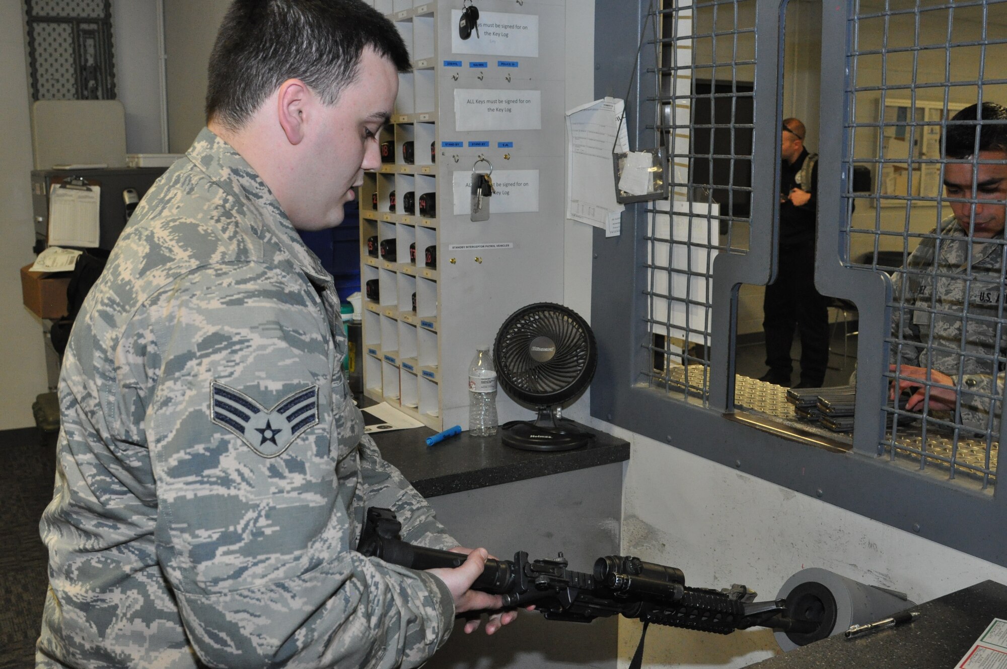 Senior Airman Levy Byler, an 88th SFS armorer, receives a weapon for a SFS Defender coming off duty from his shift Feb. 17. (U.S. Air Force photo/Bryan Ripple.)