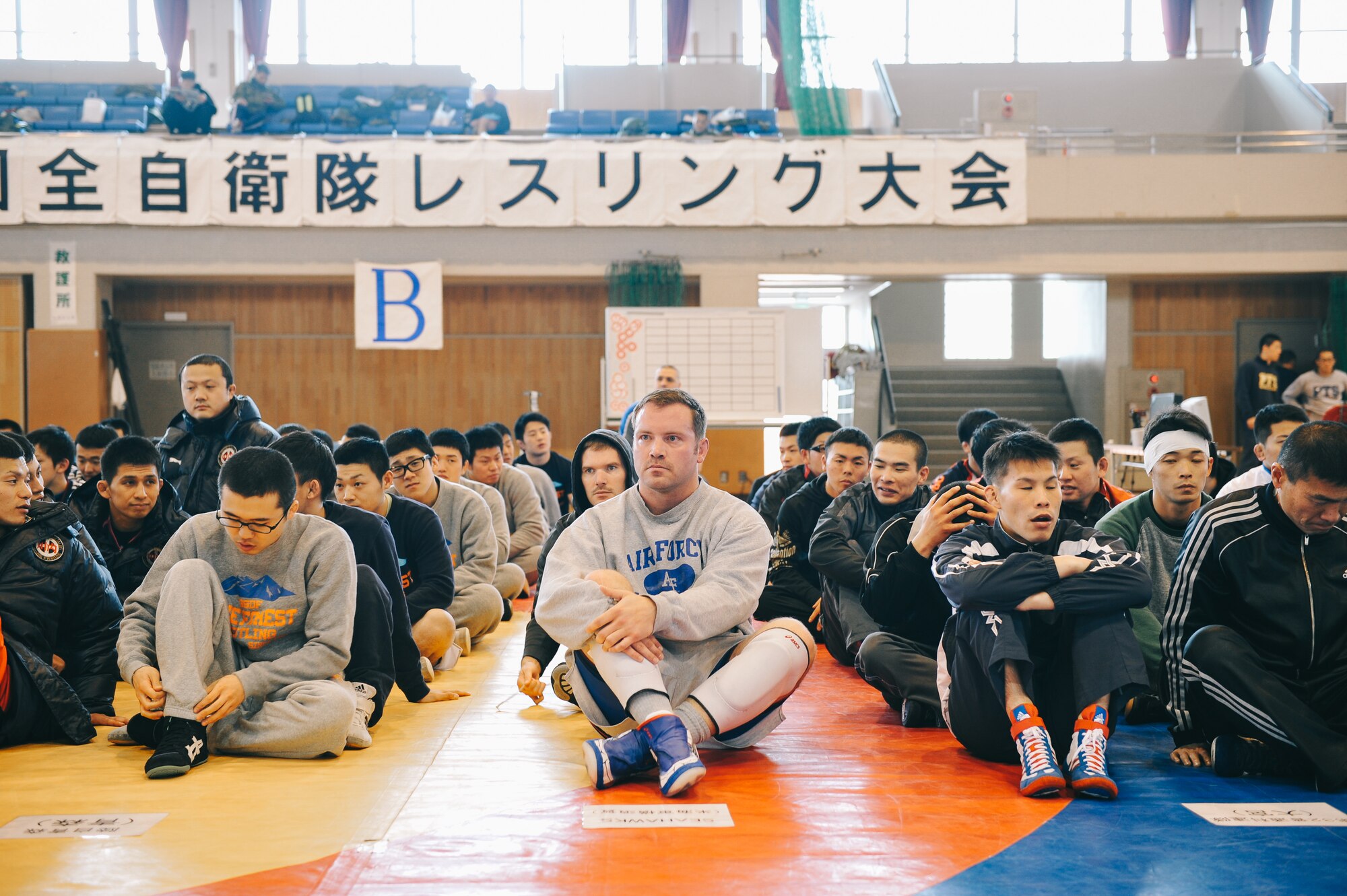 Participants of the Japan Ground Self-Defense Force All Japan Masters Wrestling Games sit before the start of the opening ceremony, March 5, 2016, at Camp Asaka, Japan. The annual tournament invited competitors throughout JSDF and U.S. military installations in Japan to participate. (U.S. Air Force photo by Airman 1st Class Delano Scott/Released)