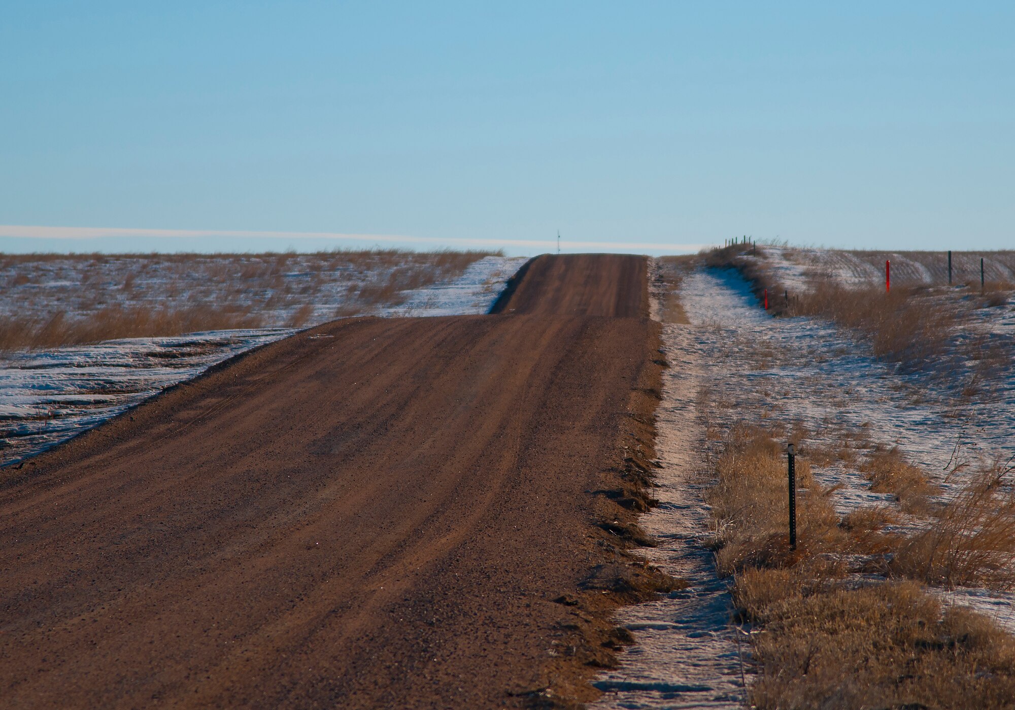This photo depicts a hilly stretch of gravel road in the F.E. Warren Air Force Base, Wyo., missile complex. A combined total of more than 7 million miles is driven by Mighty Ninety Airmen annually. Much of the driving is done over roads like these, which can be especially hazardous in the winter, so all base personnel traveling in the missile complex receive specialized training for these conditions. (U.S. Air Force photo by Senior Airman Jason Wiese)