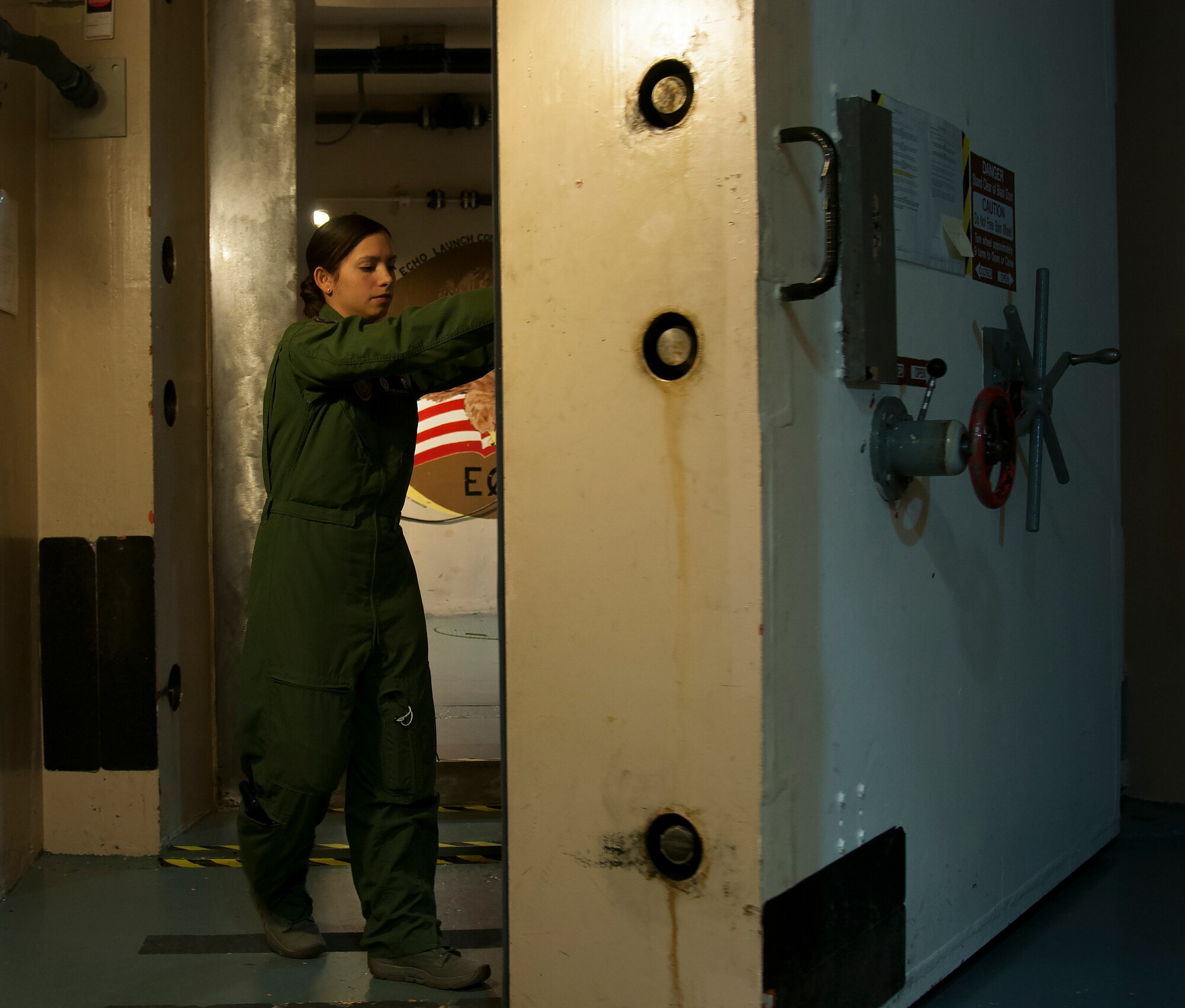 First Lt. Pamela Blanco-Coca, 319th Missile Squadron missile combat crew commander, closes the blast door underground at a Missile Alert Facility in the F.E. Warren Air Force Base, Wyo., missile complex Feb. 9, 2016. Heavy blast doors add to the survivability of the capsules and crews, in turn improving the ICBM force's deterrence capability. (U.S. Air Force photo by Senior Airman Jason Wiese)