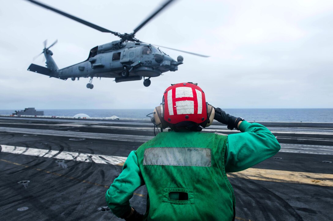Navy Petty Officer 3rd Class Elizabeth Manrique salutes an MH-60R Sea Hawk helicopter assigned to the Raptors of Helicopter Maritime Strike Squadron 71 after liftoff from the flight deck of the aircraft carreir USS John C. Stennis in the South China Sea, March 5, 2016. Manrique is an aviation structural mechanic. Navy photo by Petty Officer 3rd Class Kenneth Rodriguez Santiago