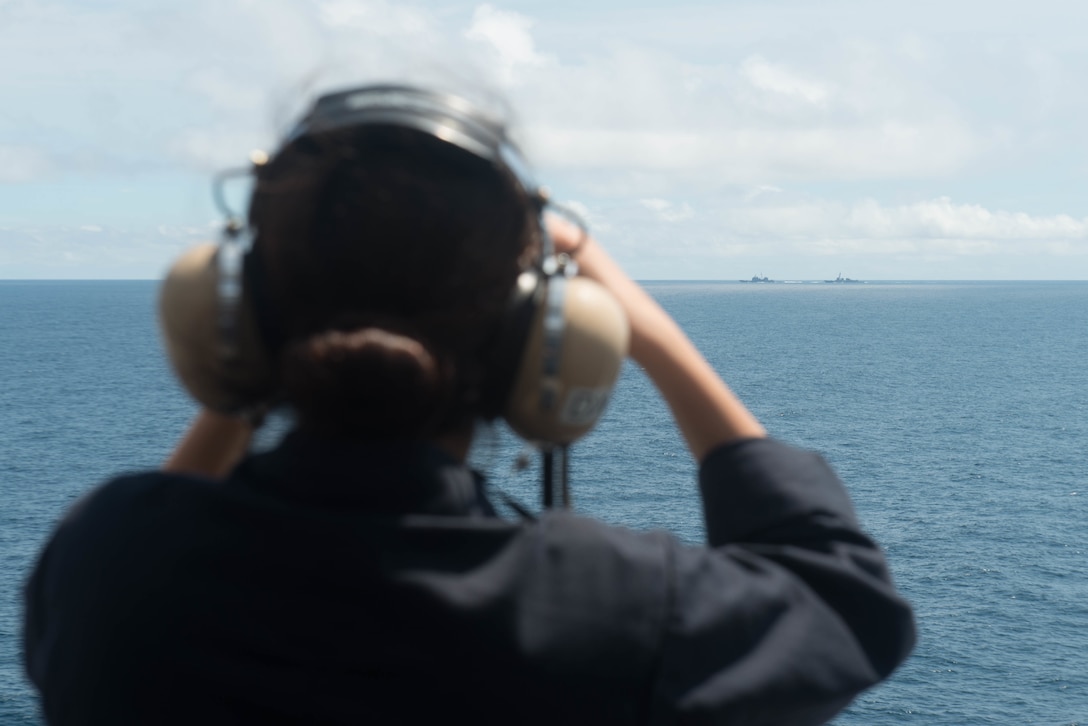 Navy Seaman Destiny Mercado looks out at the guided-missile cruiser USS Antietam and the guided-missile destroyer USS Chung-Hoon from the superstructure of the aircraft carrier USS John C. Stennis in the South China Sea, March 6, 2016. Navy photo by Petty Officer 2nd Class Jonathan Jiang