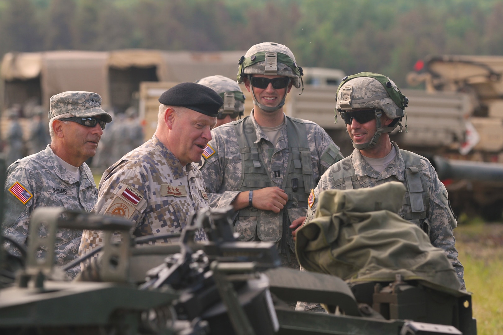 Maj. Gen. Gregory J. Vadnais, adjutant general and director of Military and Veterans Affairs for the Michigan National Guard, and Lt. Gen. Raimonds Graube, Latvian Chief of Defense, discuss the capabilities of the M777A1 howitzer with a gun crew of Alpha Battery, 1st Battalion, 119th Field Artillery Regiment, during the Exportable Combat Training Capability exercise at Camp Grayling Joint Maneuver Training Center, Mich., July 14, 2014. 
