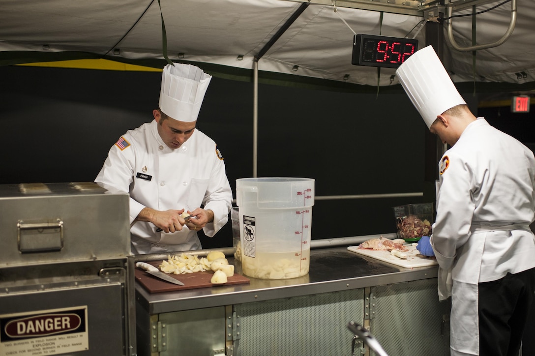 U.S. Army Reserve Culinary Arts Team members Staff Joseph Parker, left, and Staff Sgt. Jeffery Vaughn, prepare food in the early stages of the Military Hot Food Kitchen category at the 41st Annual Military Culinary Arts Competitive Training Event, March 10, 2016, at Fort Lee, Va. The team prepared Roasted Golden and Burgundy Beet Salad, Coq au Vin Nuevo (Chicken braised in red wine), and Molten Lava Cake working on a Mobile Kitchen Trailer for 45 dining guests. (U.S. Army photo by Timothy L. Hale/Released)