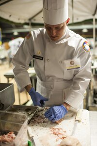 U.S. Army Reserve Culinary Arts Team member, Staff Sgt. Jeffery Vaughn, prepares chicken during the Military Hot Food Kitchen category at the 41st Annual Military Culinary Arts Competitive Training Event, March 10, 2016, at Fort Lee, Va. The team prepared Roasted Golden and Burgundy Beet Salad, Coq au Vin Nuevo (Chicken braised in red wine), and Molten Lava Cake working on a Mobile Kitchen Trailer for 45 dining guests. (U.S. Army photo by Timothy L. Hale/Released)