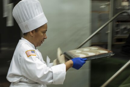 U.S. Army Reserve Culinary Arts Team member Staff Aqueelah James, moves part of her dessert to the oven during the Military Hot Food Kitchen category at the 41st Annual Military Culinary Arts Competitive Training Event, March 10, 2016, at Fort Lee, Va. The team prepared Roasted Golden and Burgundy Beet Salad, Coq au Vin Nuevo (Chicken braised in red wine), and Molten Lava Cake working on a Mobile Kitchen Trailer for 45 dining guests. (U.S. Army photo by Timothy L. Hale/Released)