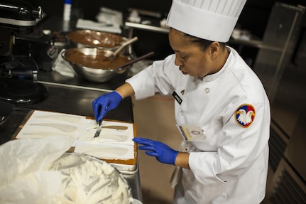 U.S. Army Reserve Culinary Arts Team member Staff Aqueelah James, works on her dessert during the Military Hot Food Kitchen category at the 41st Annual Military Culinary Arts Competitive Training Event, March 10, 2016, at Fort Lee, Va. The team prepared Roasted Golden and Burgundy Beet Salad, Coq au Vin Nuevo (Chicken braised in red wine), and Molten Lava Cake working on a Mobile Kitchen Trailer for 45 dining guests. (U.S. Army photo by Timothy L. Hale/Released)