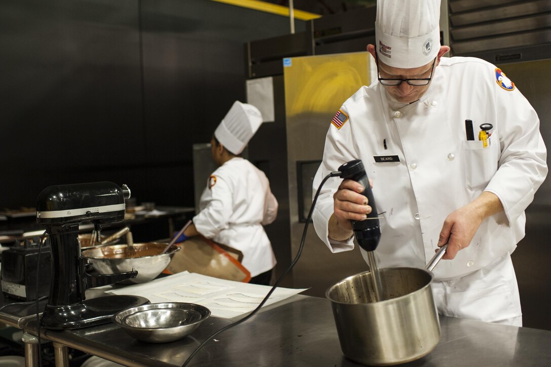 U.S. Army Reserve Culinary Arts Team manager, Chief Warrant Officer 2 Colby Beard, with the 11th Theater Aviation Command, mixes ingredients during the Military Hot Food Kitchen category at the 41st Annual Military Culinary Arts Competitive Training Event, March 10, 2016, at Fort Lee, Va. The team prepared Roasted Golden and Burgundy Beet Salad, Coq au Vin Nuevo (Chicken braised in red wine), and Molten Lava Cake working on a Mobile Kitchen Trailer for 45 dining guests. (U.S. Army photo by Timothy L. Hale/Released)