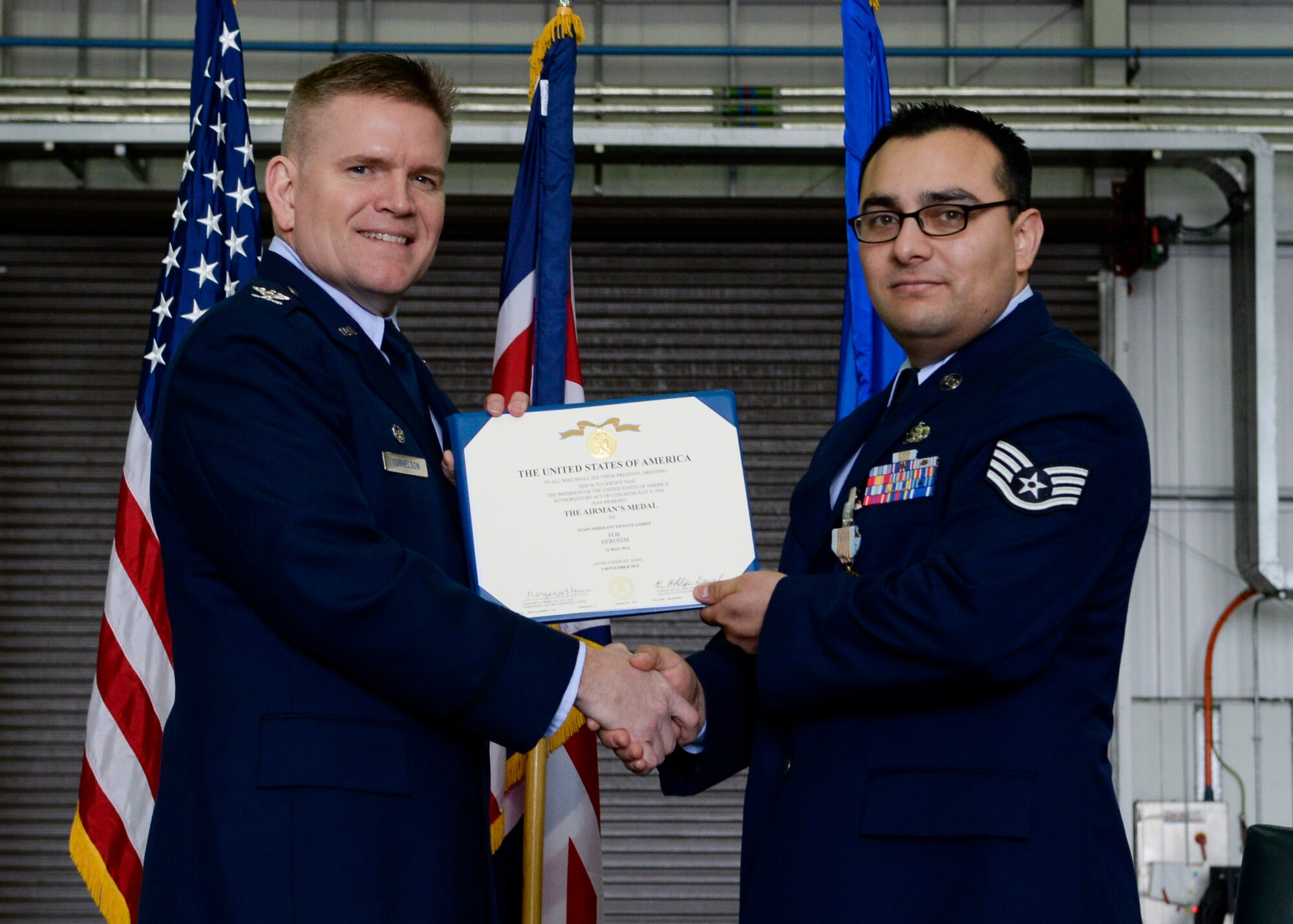 U.S. Air Force Col. Thomas D. Torkelson, 100th Air Refueling Wing commander, presents Staff Sgt. Vicente Gomez, 100th Aircraft Maintenance Squadron crew chief, with the Airman’s Medal certificate during a ceremony March 11, 2016, on RAF Mildenhall, England. Gomez received the honor for his courageous acts performed on May 12, 2014 by saving the lives of two victims from a potentially fatal car accident. (U.S. Air Force photo by Senior Airman Victoria H. Taylor/Released)