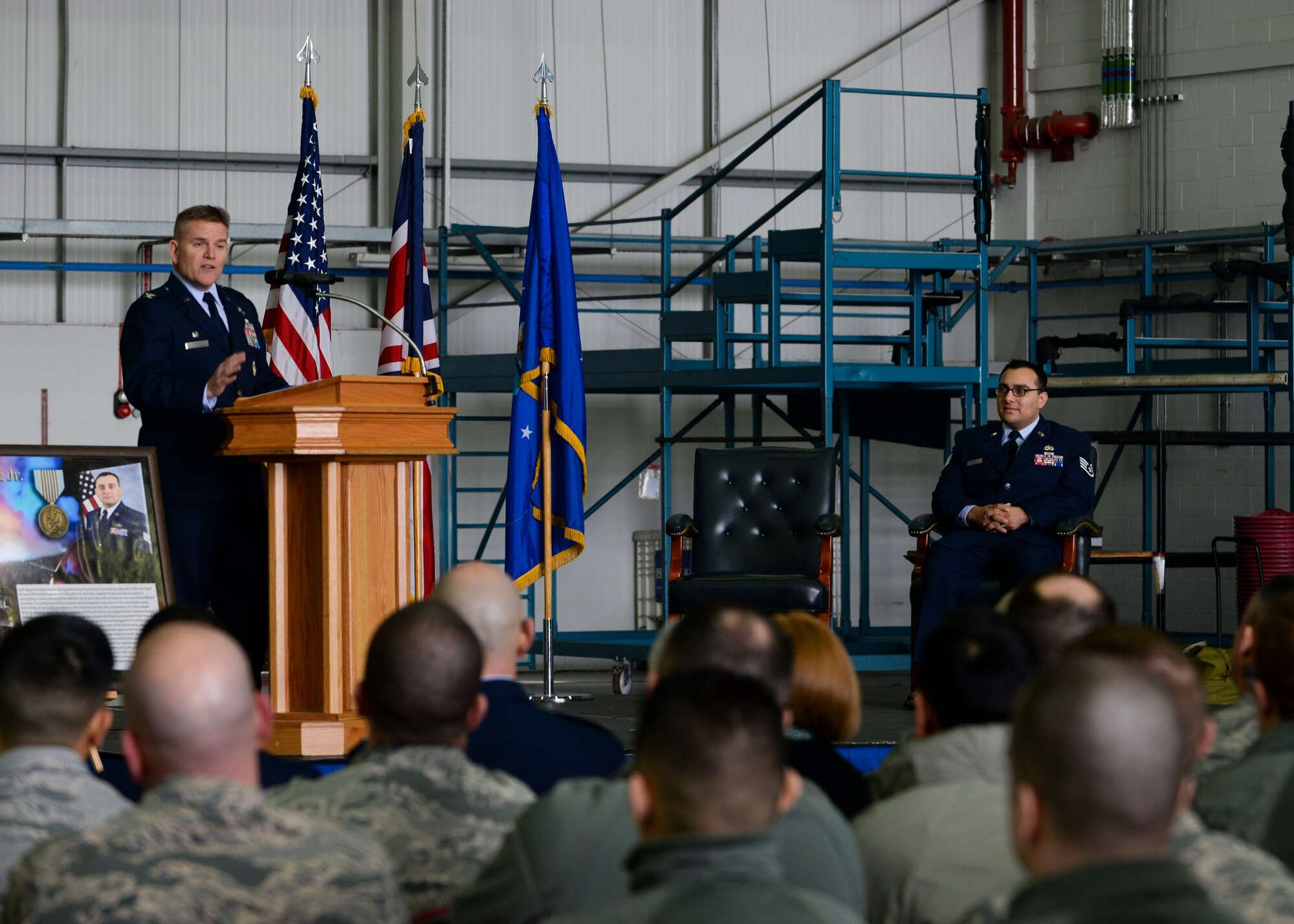 U.S. Air Force Col. Thomas D. Torkelson, 100th Air Refueling Wing commander, recounts the heroic acts of Staff Sgt. Vicente Gomez, 100th Aircraft Maintenance Squadron crew chief, during a ceremony March 11, 2016, on RAF Mildenhall, England. Gomez was presented with the Airman’s Medal for risking his life to save two others near RAF Mildenhall on May 12, 2014. (U.S. Air Force photo by Senior Airman Victoria H. Taylor/Released)