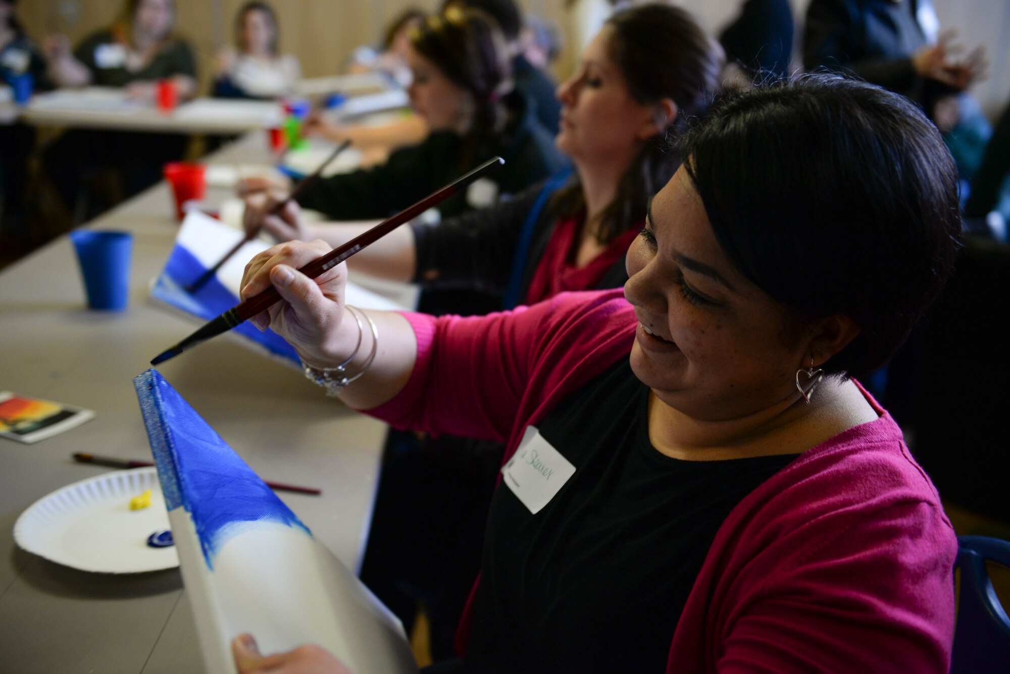 Team Mildenhall spouses paint canvases during a Hearts Apart event for families of deployed Airmen March 10, 2016, at the Bob Hope Community Center on RAF Mildenhall, England. This month the RAF Mildenhall Top Three Fellowship hosted the monthly event which helps bring Team Mildenhall families closer together during times of separation. (U.S. Air Force photo by Staff Sgt. Micaiah Anthony/Released)
