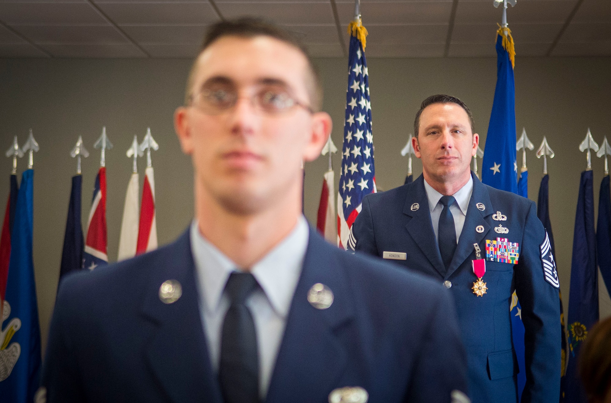 Chief Master Sgt. Vance Kondon looks on as his son, Senior Airman Vance Kondon, participates in his retirement ceremony at the Community Commons on Joint Base Andrews, Md.,  March 11, 2016.  The Chief retired after 30 years of service, spending two years as command chief at JBA. (U.S. Air Force photo by Senior Airman Mariah Haddenham / Released)