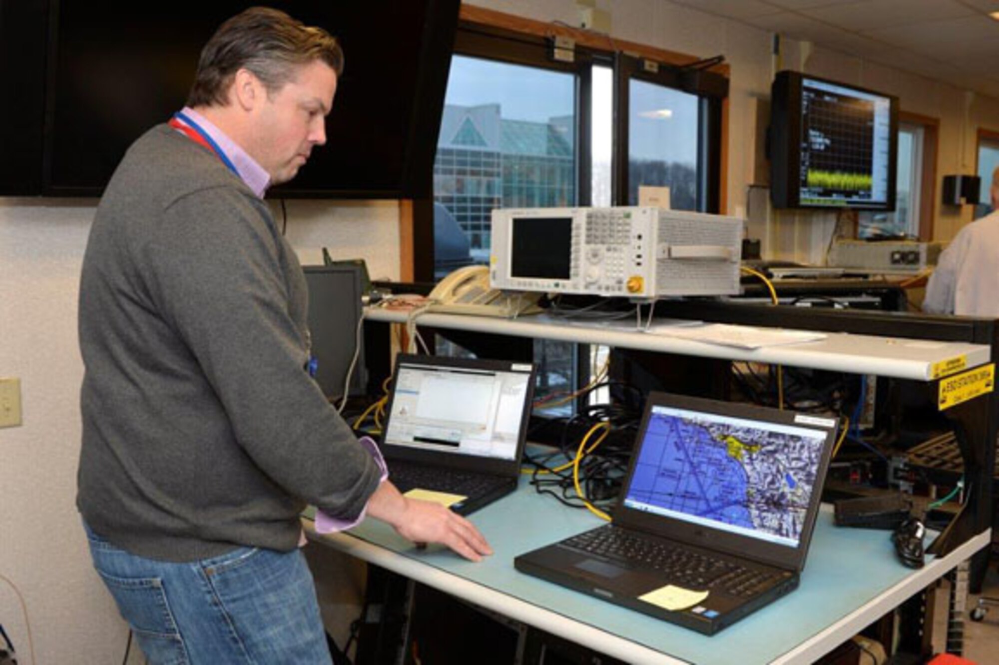 Matt Ryan, MITRE engineer, assesses the performance of Air Force user
applications during satellite testing of a protected tactical waveform in
January at MIT Lincoln Laboratory, Hanscom Air Force Base, Mass. Hanscom's
Satellite Terminal Program Office, in collaboration with MITRE and MIT LL is
working to demonstrate that a third-party PTW modem could integrate with an
existing airborne communications terminal and connect through a commercial
satellite. (Photo courtesy of MIT Lincoln Laboratory)
