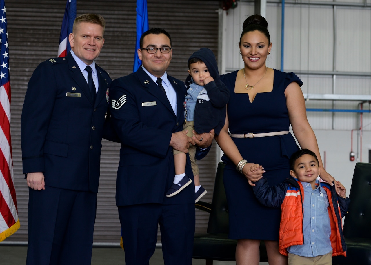 U.S. Air Force Col. Thomas D. Torkelson, 100th Air Refueling Wing commander, left, Staff Sgt. Vicente Gomez, 100th Aircraft Maintenance Squadron crew chief, and his wife and children pose for a photo during a ceremony March 11, 2016, on RAF Mildenhall, England. Gomez was presented with the Airman’s Medal for risking his life to save two others near RAF Mildenhall on May 12, 2014. (U.S. Air Force photo by Senior Airman Victoria H. Taylor/Released)