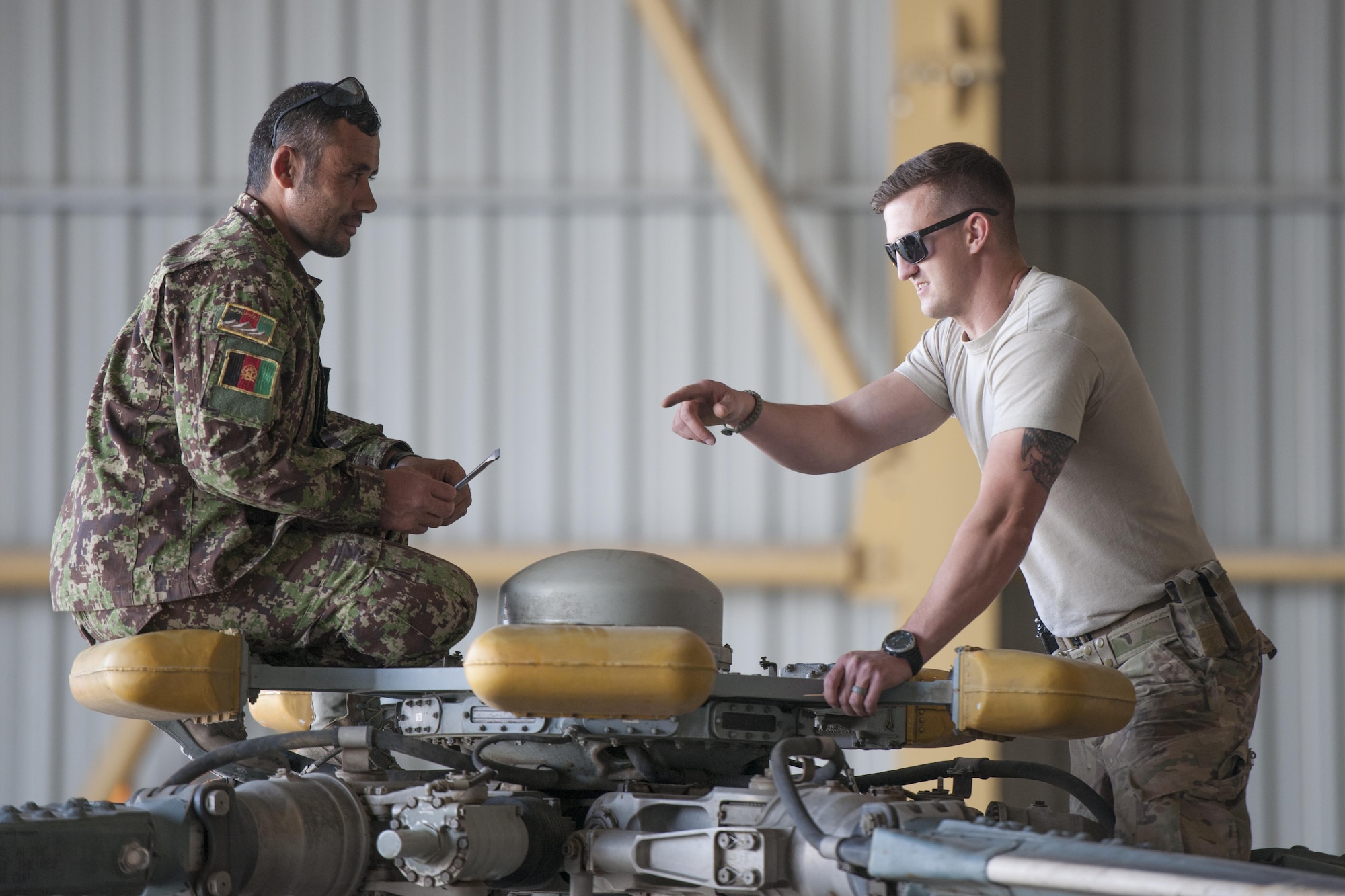 Tech. Sgt. Richard Embrey, Train Advise Assist Command - Air Mi-17 Intermediate Maintenance Squadron advisor, advises an Afghan Air Force member during a 100-hour inspection on an Mi-17 at Kandahar Airfield, March 2, 2016. As a functional command, TAAC-Air assists our Afghan partners to develop a professional, capable and sustainable force. (U.S. Air Force photo/Tech. Sgt. Robert Cloys)