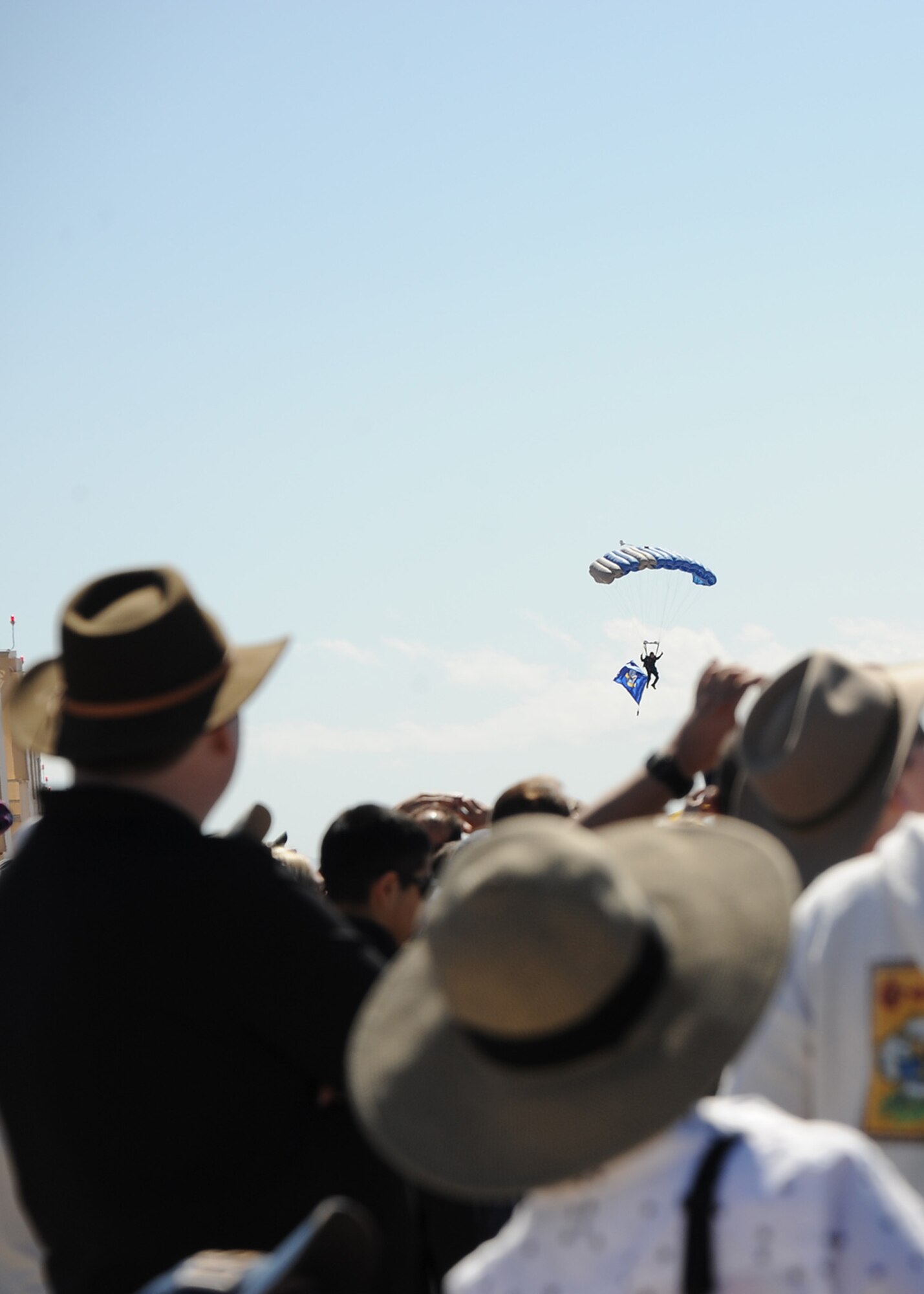 Spectators watch as the U.S. Air Force Skydiving Team, Wings of Blue, preform during the opening ceremony of the Thunder and Lightning over Arizona Open House at Davis-Monthan Air Force Base, Ariz., March 12, 2016. The demonstration team travels across the country to airshows, sporting events, and other venues to represent the Air Force in precision parachuting. (U.S. Air Force photo by Airmen 1st Class Ashley N. Steffen/Released)