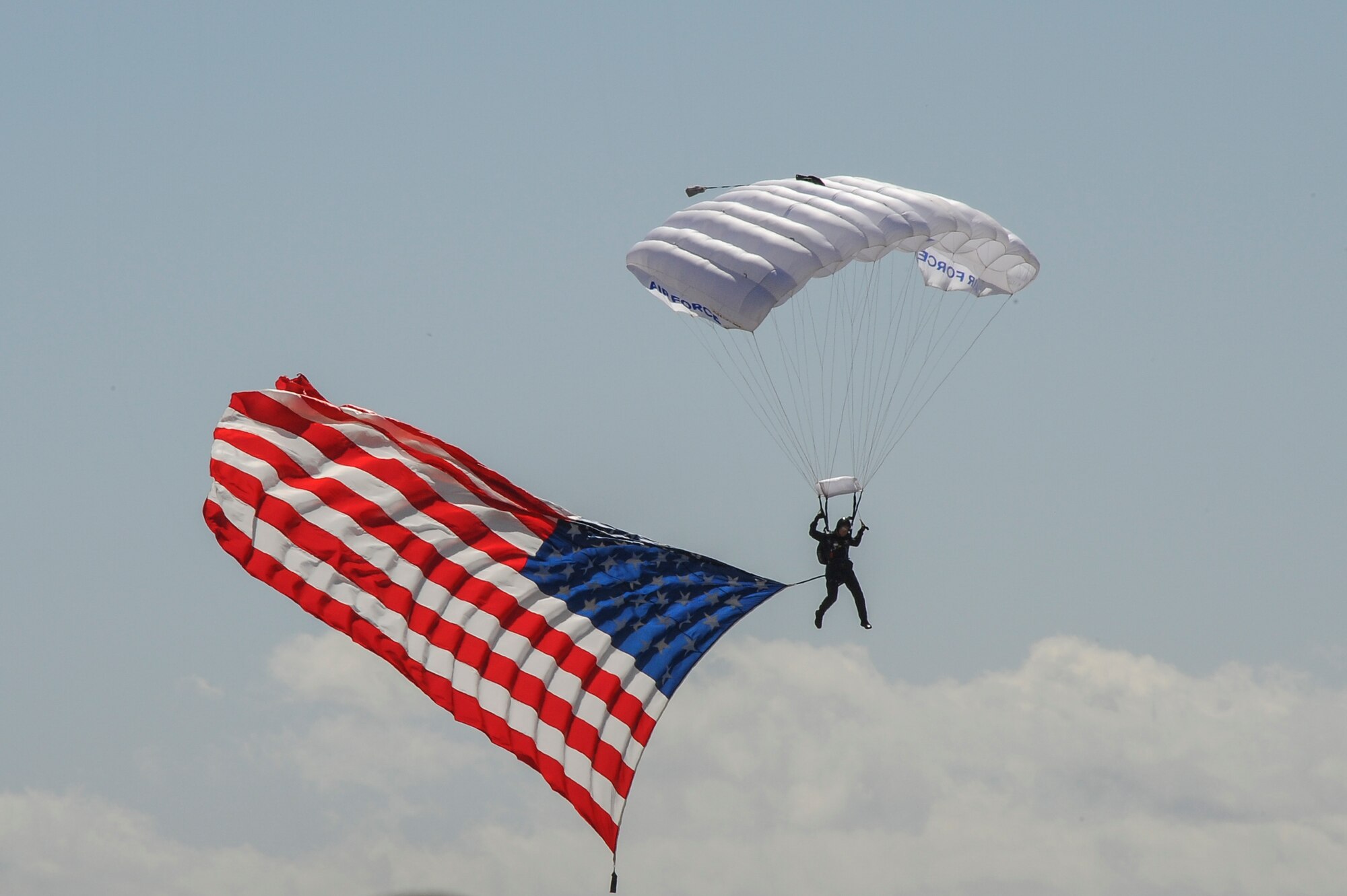 U.S. Air Force Master Sgt. James Cane, U.S Air Force Skydiving Team, Wings of Blue, lands with the American flag during Thunder and Lightning over Arizona Open House at Davis-Monthan Air Force Base, Ariz., March 12, 2016. The Wings of Blue Demonstration Team performs at more than 50 special events in front of over 2 million spectators a year. Members of the team serve primarily as jumpmasters and instructors, devoting most of their time to teaching students about parachuting and training them to make unassisted freefall skydives. (U.S. Air Force photo by Airman 1st Class Mya M. Crosby/Released)