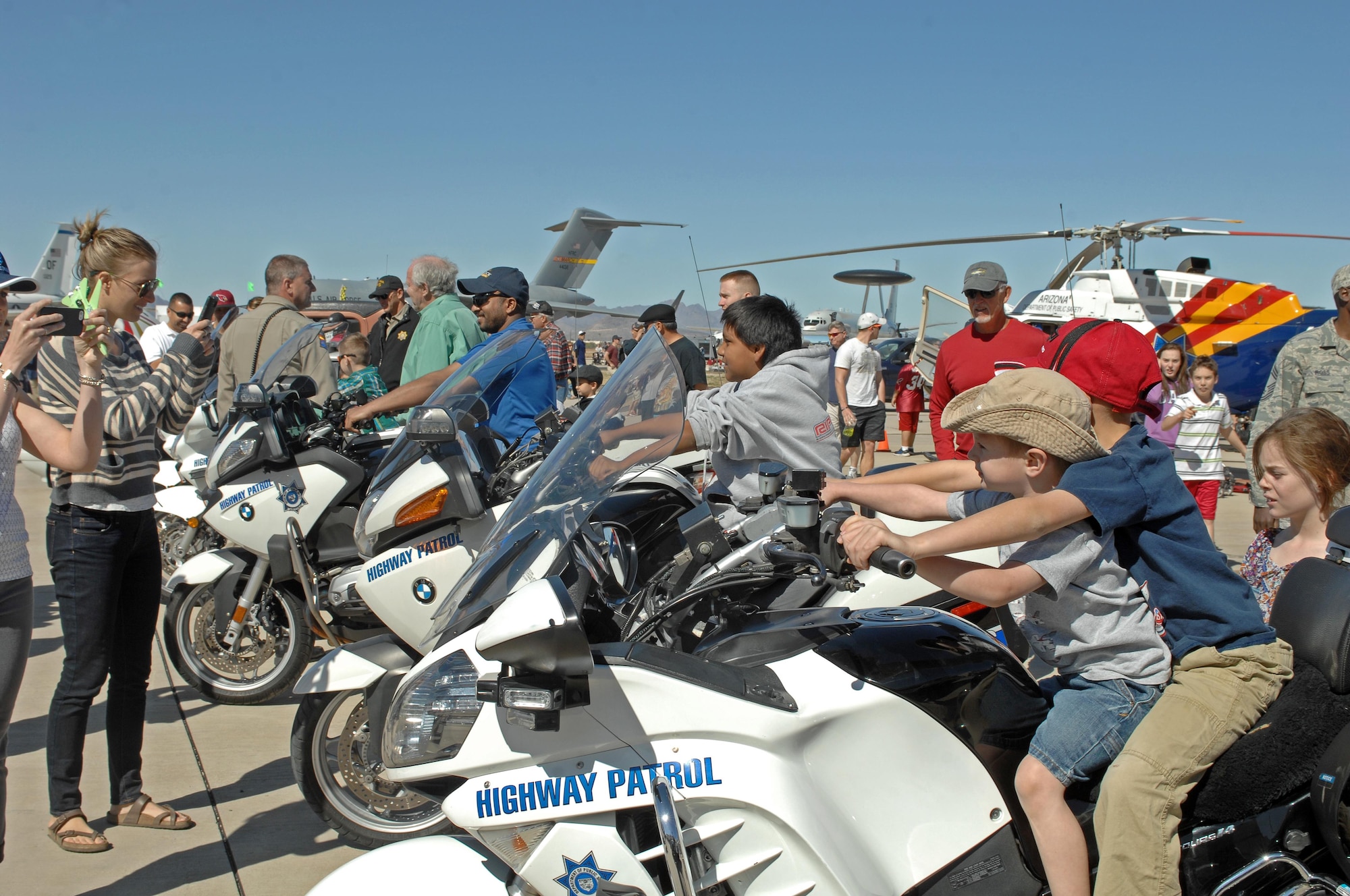 Children sit on Arizona Highway Patrol Motorcycles while parents take photographs during the Thunder and Lightning over Arizona Open House at Davis-Monthan Air Force Base, Ariz., March 12, 2016. The mission of the Arizona Highway Patrol is to ensure the safe and expeditious use of the highway transportation system for the public and to provide assistance to local and county law enforcement agencies. (U.S. Air Force photo by Senior Airman Camilla Elizeu/Released)