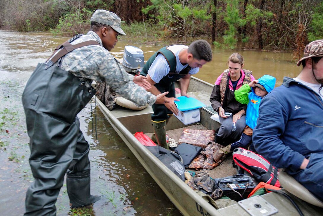 Army Sgt. Malcom Beavers, left, delivers medical supplies to Spencer Barrett, center, so he can deliver them to the family awaiting them, in Columbia, La., March 10, 2016. Beavers is a petroleum specialist assigned to the Louisiana National Guard’s Forward Support Company, 528th Engineer Battalion. Louisiana Army National Guard photo by Sgt. Noshoba Davis