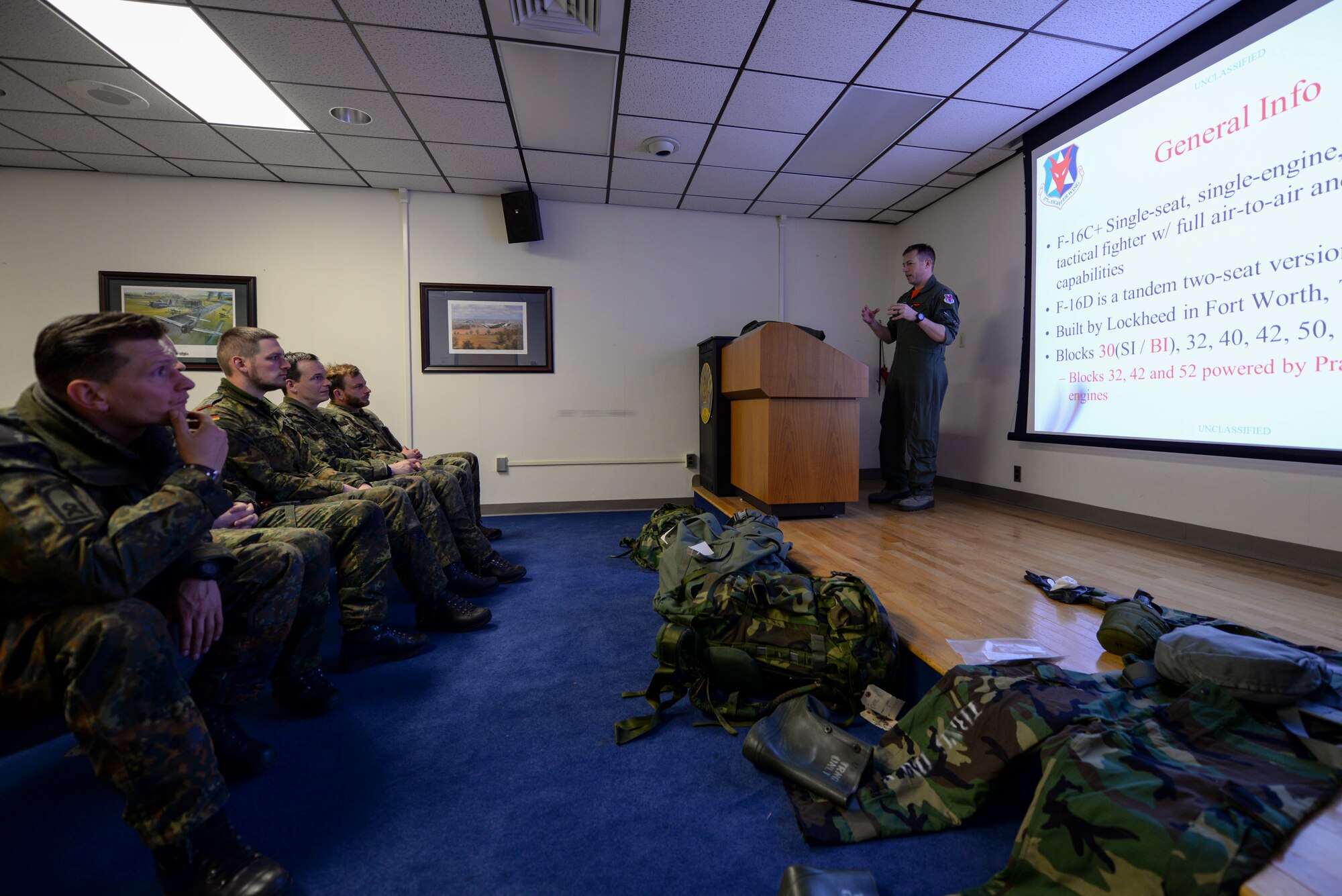 A picture of U.S. Air Force Maj. Benjamin Robbins, F-16 fighter pilot with the New Jersey Air National Guard's 177th Fighter Wing, giving an F-16 Fighting Falcon familiarization brief to German armed forces joint terminal attack controllers (JTACs).