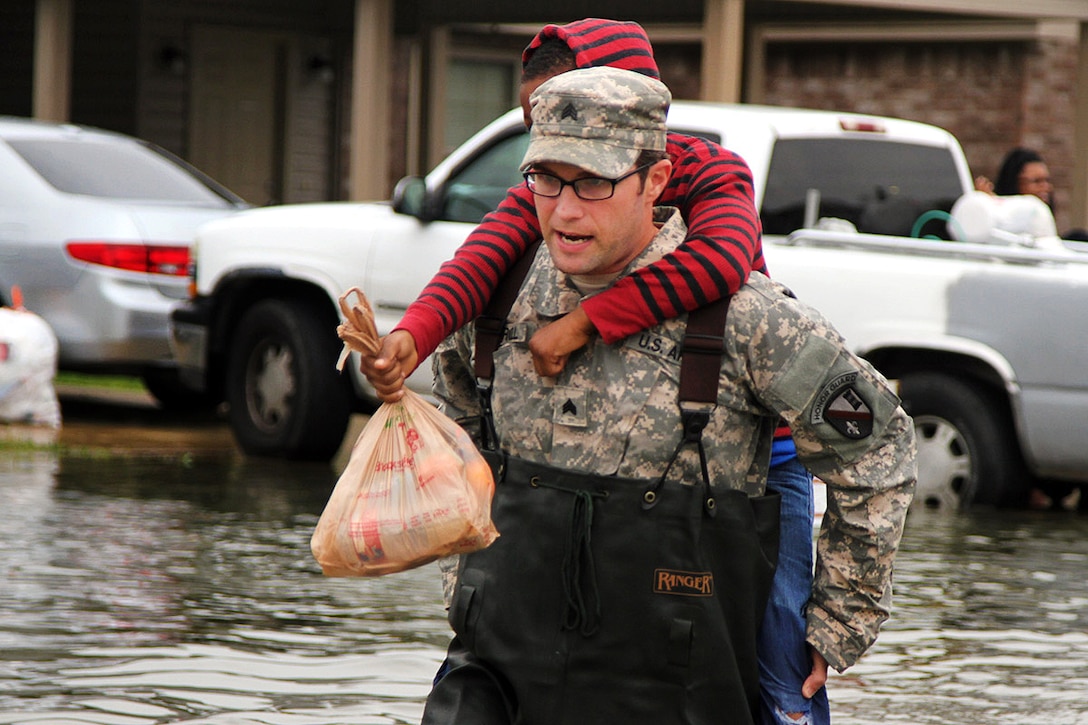 Army Sgt. Jason C. Carroll carries a young child through flooded streets in Monroe, La., March 10, 2016. Carroll is an electronic warfare specialist assigned to the Louisiana National Guard's 528th Engineer Battalion, 225th Engineer Brigade. The unit navigated the high waters to rescue people stranded by flooding. Army National Guard photo by Spc. Tarell J. Bilbo