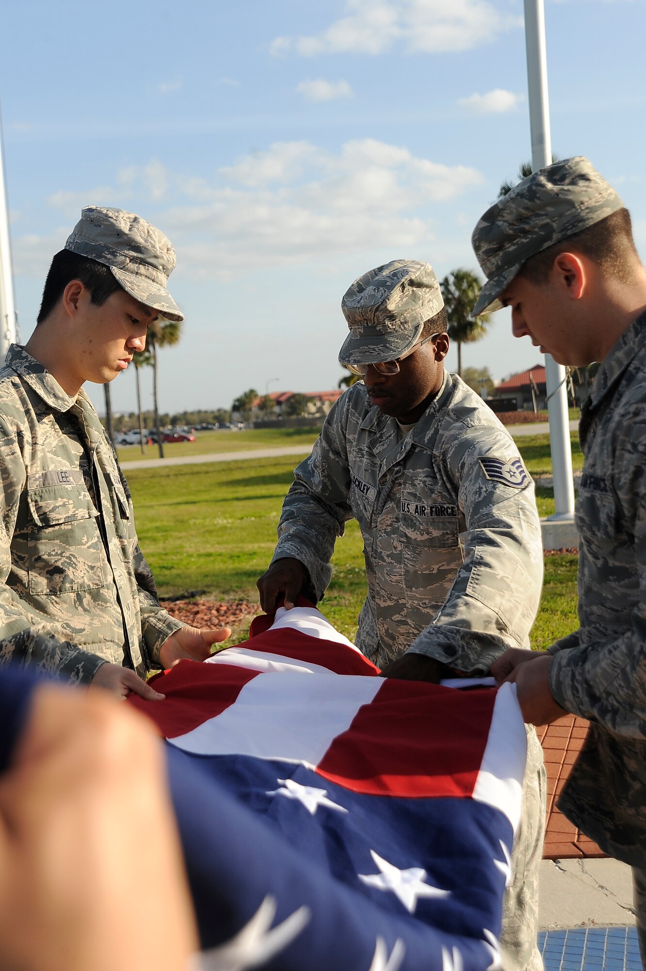 Airman 1st Class Horyeong Lee, left, Staff Sgt. Dominique Lockley, center, and Staff Sgt. Jared Metcalfe, right, flag detail members, fold the American flag during a retreat ceremony at MacDill Air Force Base Fla., March 9, 2016. Retreat is a time-honored event, which has been performed for centuries.  (U.S. Air Force photo by Airman 1st Class Mariette Adams)
