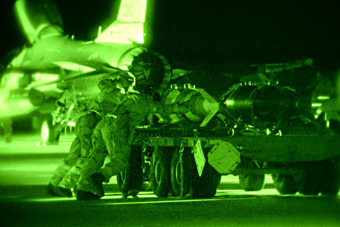 As seen through a night-vision device, airmen push munitions to be loaded onto an F-16 Fighting Falcon on the flight line during Exercise Dastardly Devil 16-1 at the Atlantic City Air National Guard Base, N.J., March 12, 2016. New Jersey Air National Guard photo by Tech. Sgt. Andrew Merlock