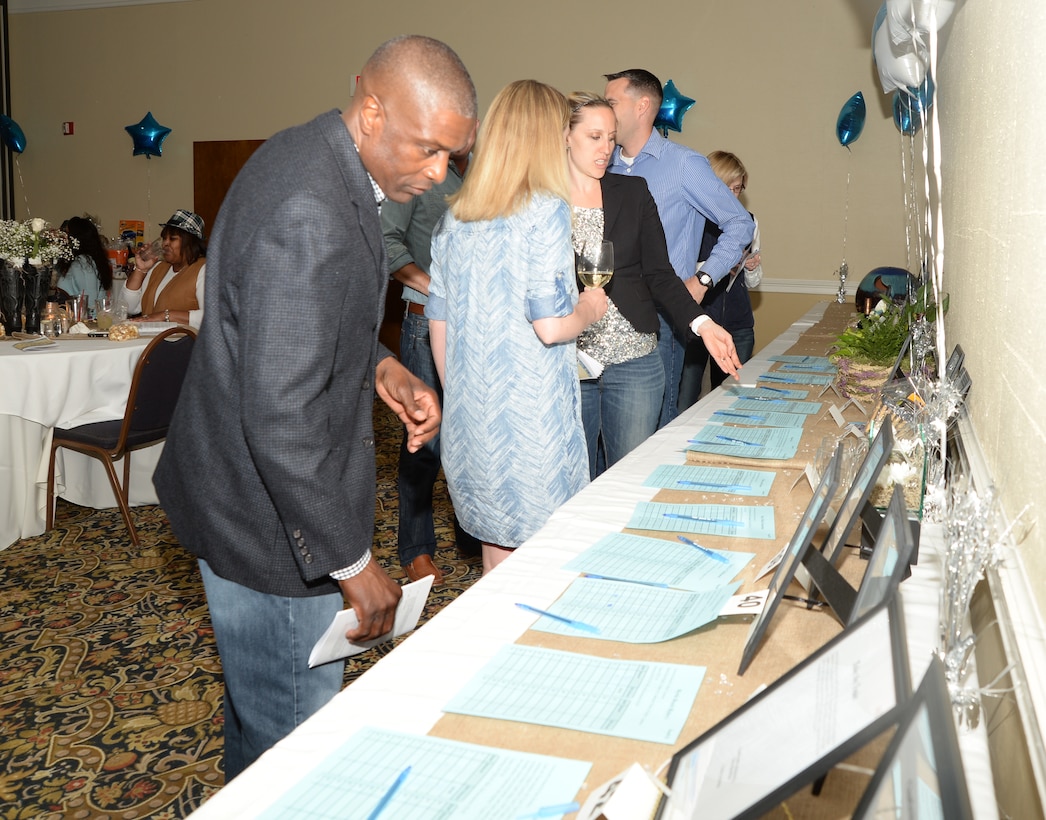 Guests check the status of silent bid items during the Denim and Diamonds Scholarship and Charity Fundraiser. The auction was held at Merry Acres Inn & Event Center recently to raise funds for military dependents, spouses and non-profit organizations.