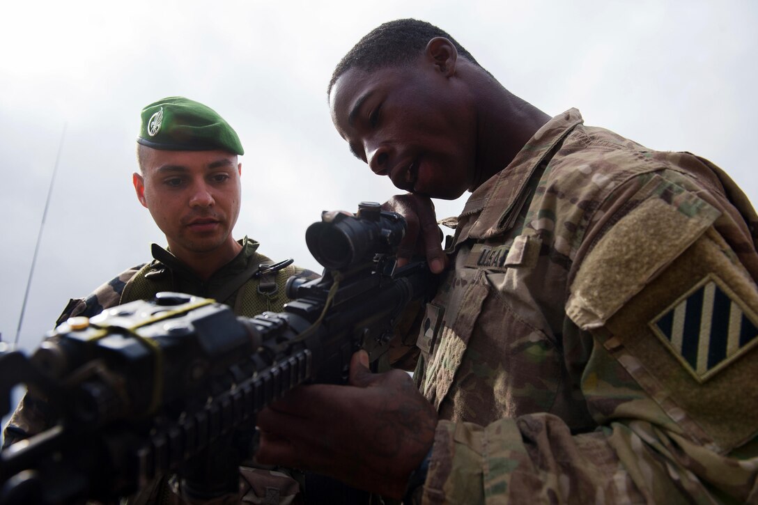 A U.S. soldier, right, demonstrates the operation of an M4 carbine rifle for a French Foreign Legion soldier at a firing range in Djibouti, March 5, 2016. Air Force photo by Tech. Sgt. Barry Loo