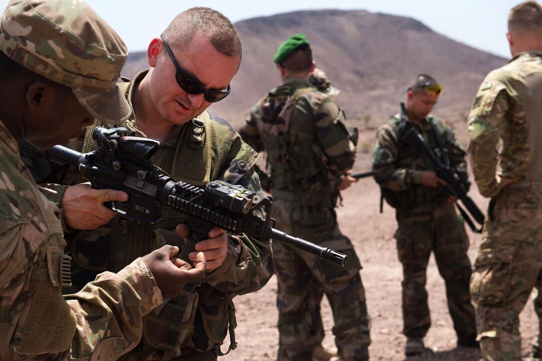 A U.S. soldier, left, teaches a French Foreign Legion soldier how to properly operate an M4 carbine rifle at a firing range in Djibouti, March 5, 2016. Air Force photo by Tech. Sgt. Barry Loo